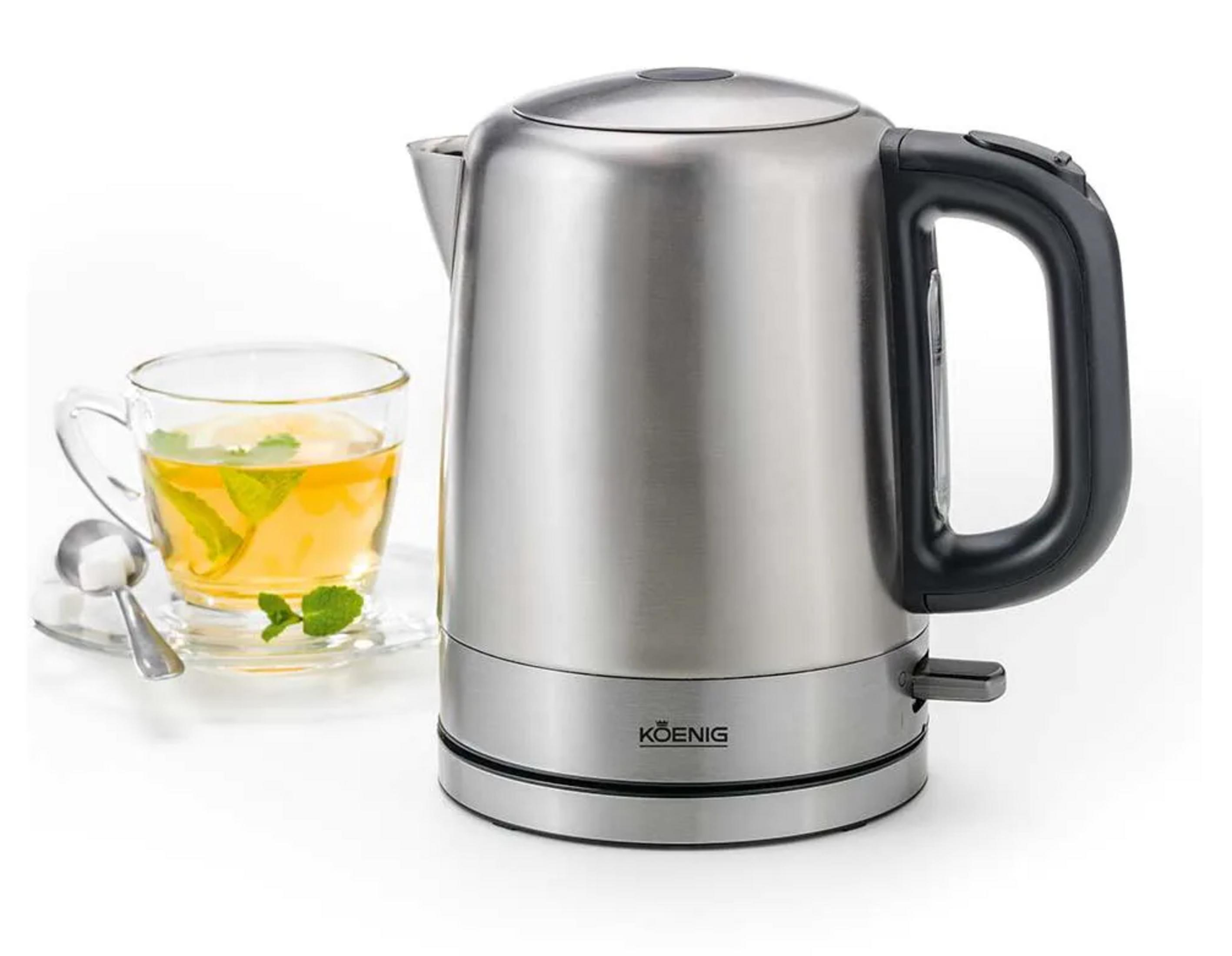 Ein silberner Wasserkocher neben einer Tasse Tee mit Minze und Zitrone.