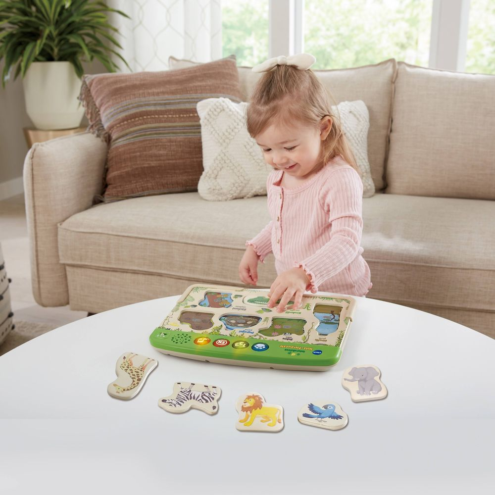 Ein kleines Mädchen spielt mit einem Tier-Puzzle auf einem Tisch.
