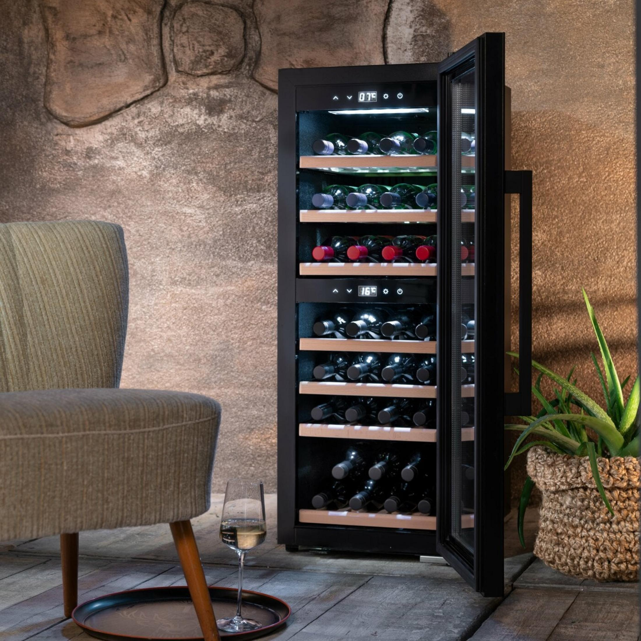 Ein Wein Kühlschrank mit offenen Türen, gefüllt mit Flaschen, daneben ein Glas Wein.