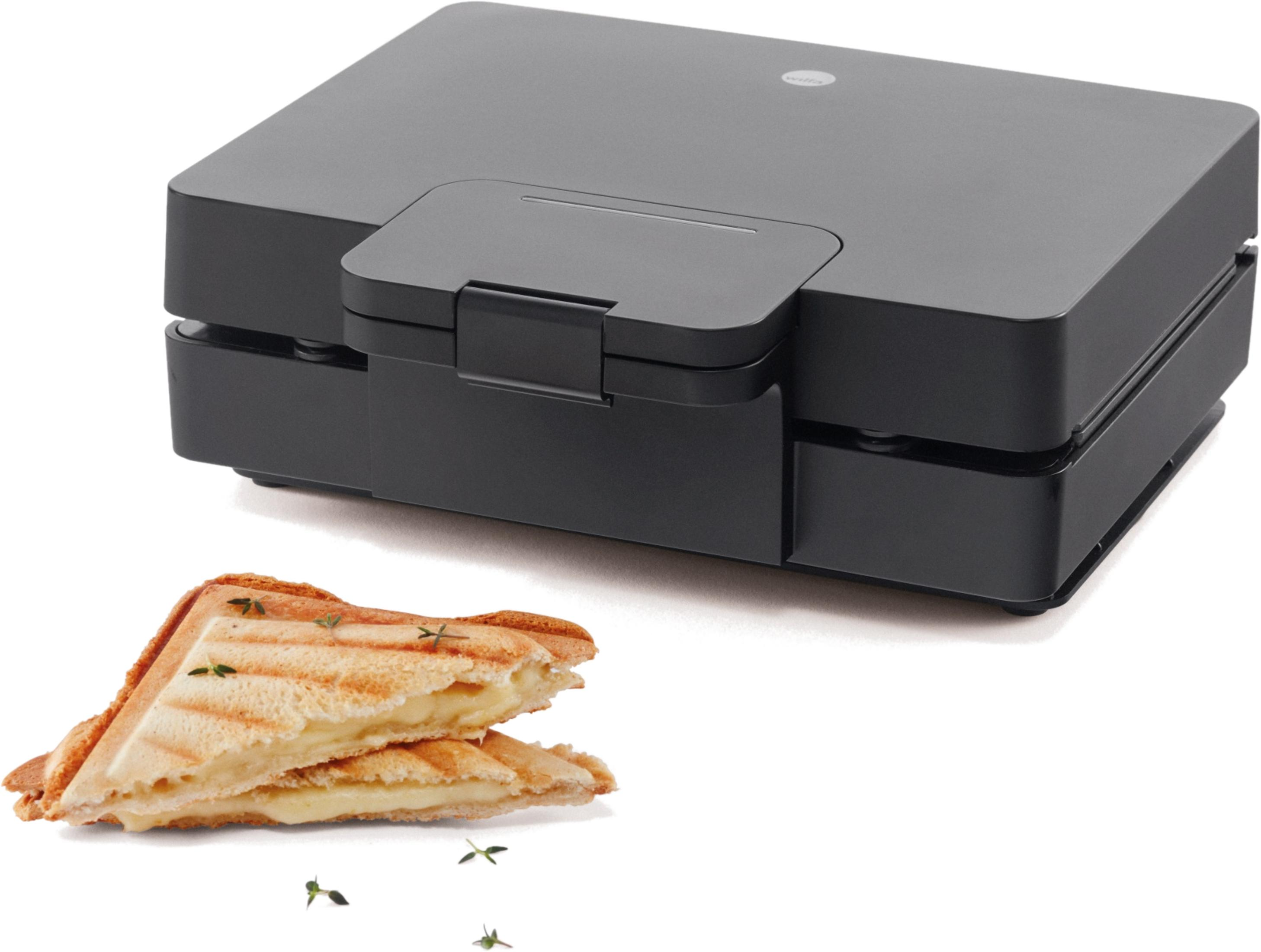 Ein schwarzer Sandwichmaker mit zwei gegrillten Sandwiches davor.