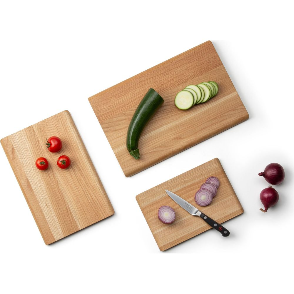 Holzschneidebretter mit Tomaten, Zucchini und Zwiebeln, teils geschnitten.