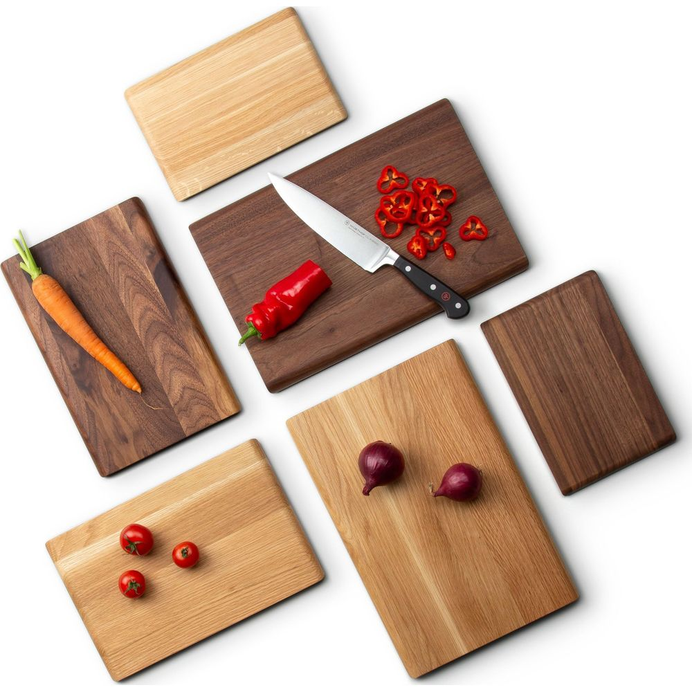Mehrere Holzschneidebretter mit Zutaten: Karotte, Tomaten, Zwiebeln, Paprika, Messer.