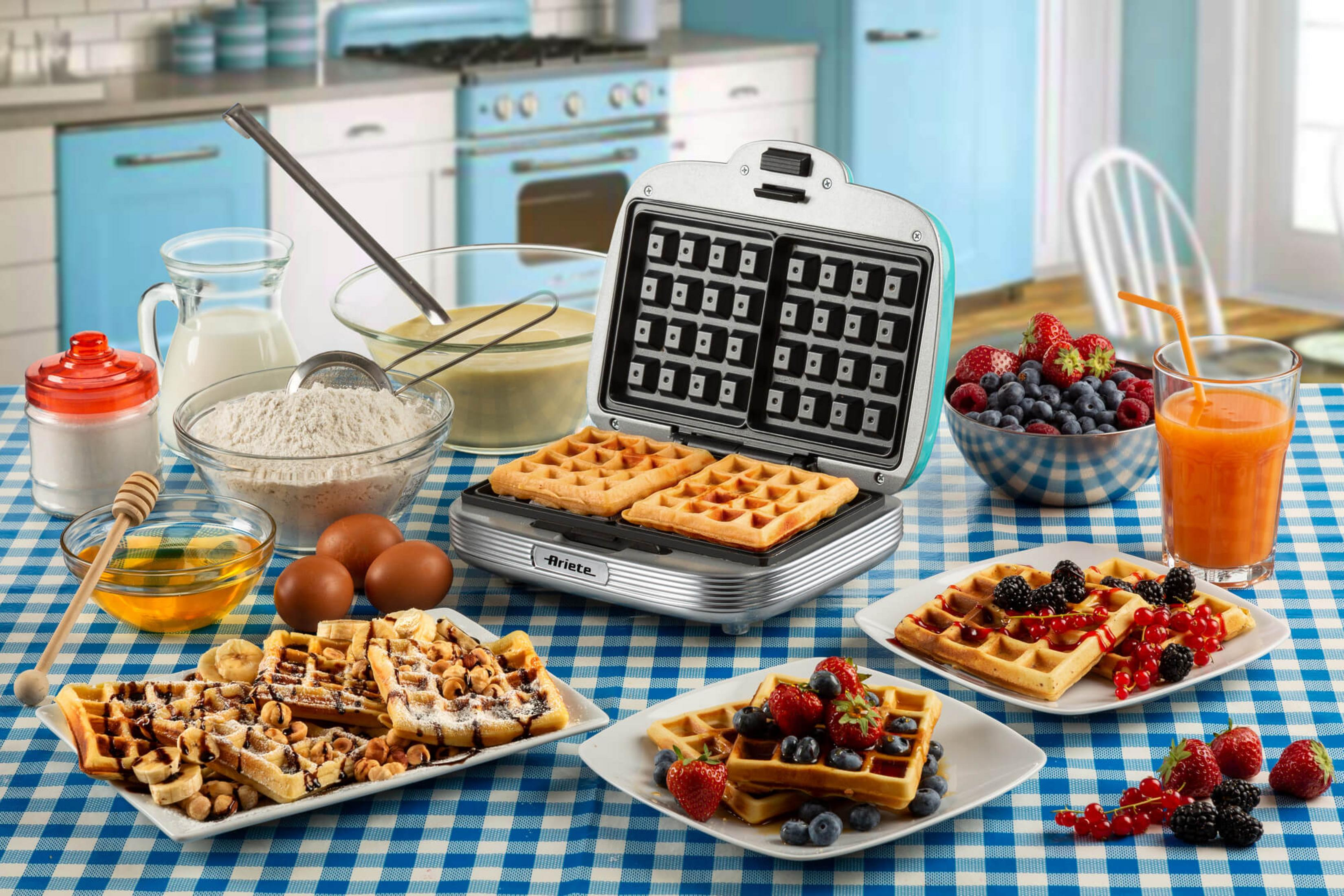 Wafelmaker met afgewerkte wafels, bessen, sap en wafel ingrediënten.