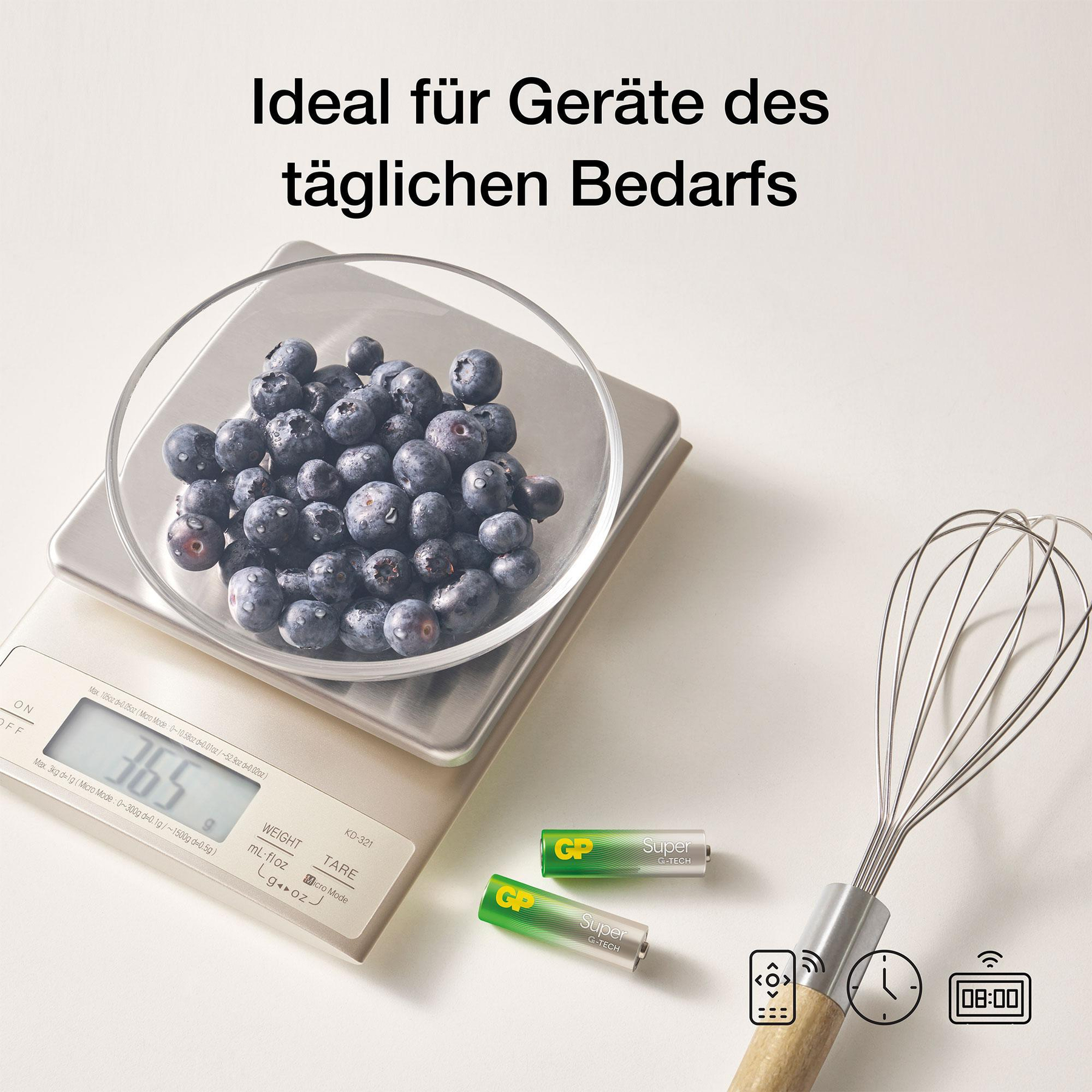Eine Waage mit Blaubeeren, zwei Batterien und einem Schneebesen.