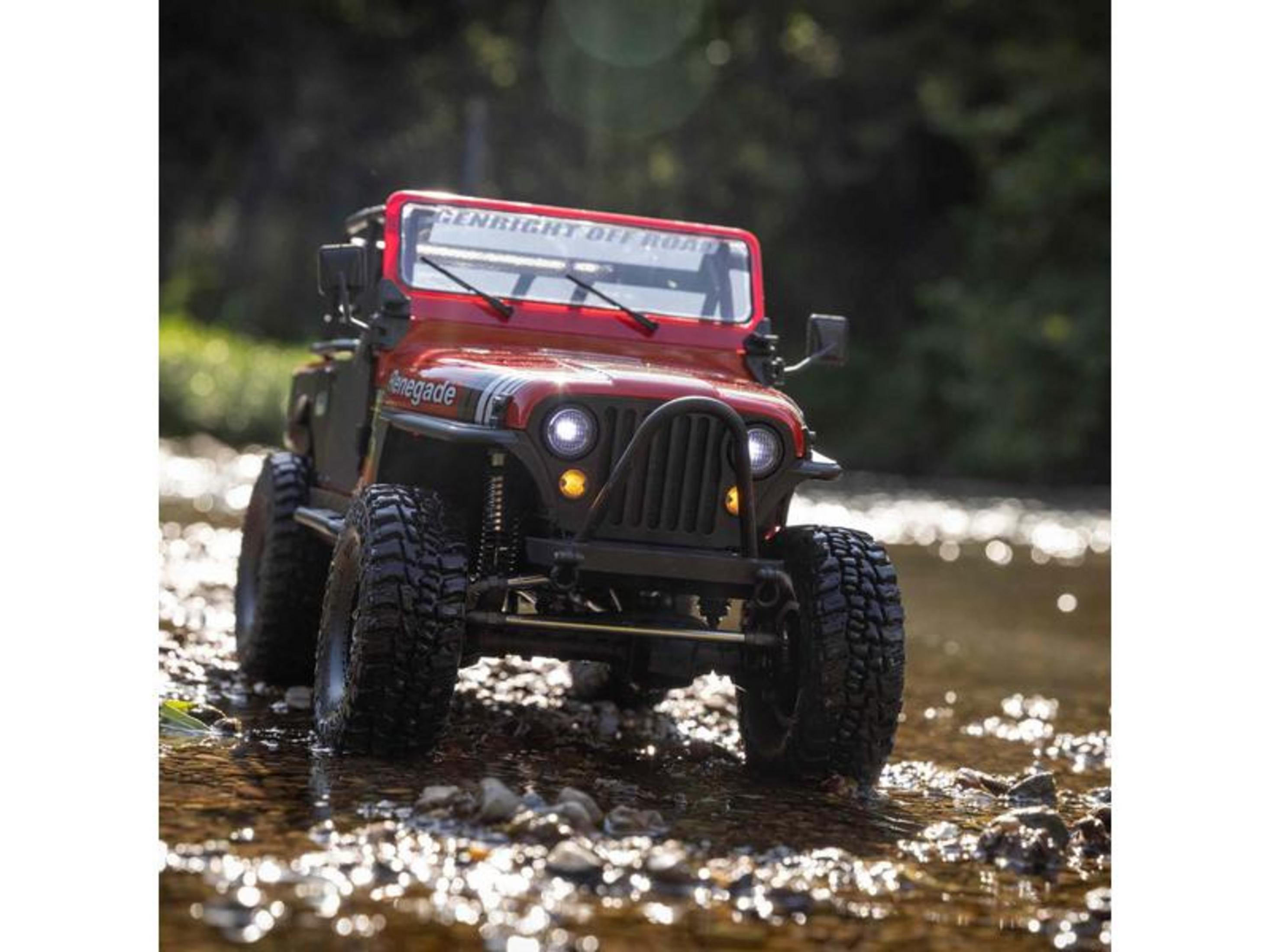 Un Jeep RC rouge traversant un ruisseau rocheux avec de l'eau.
