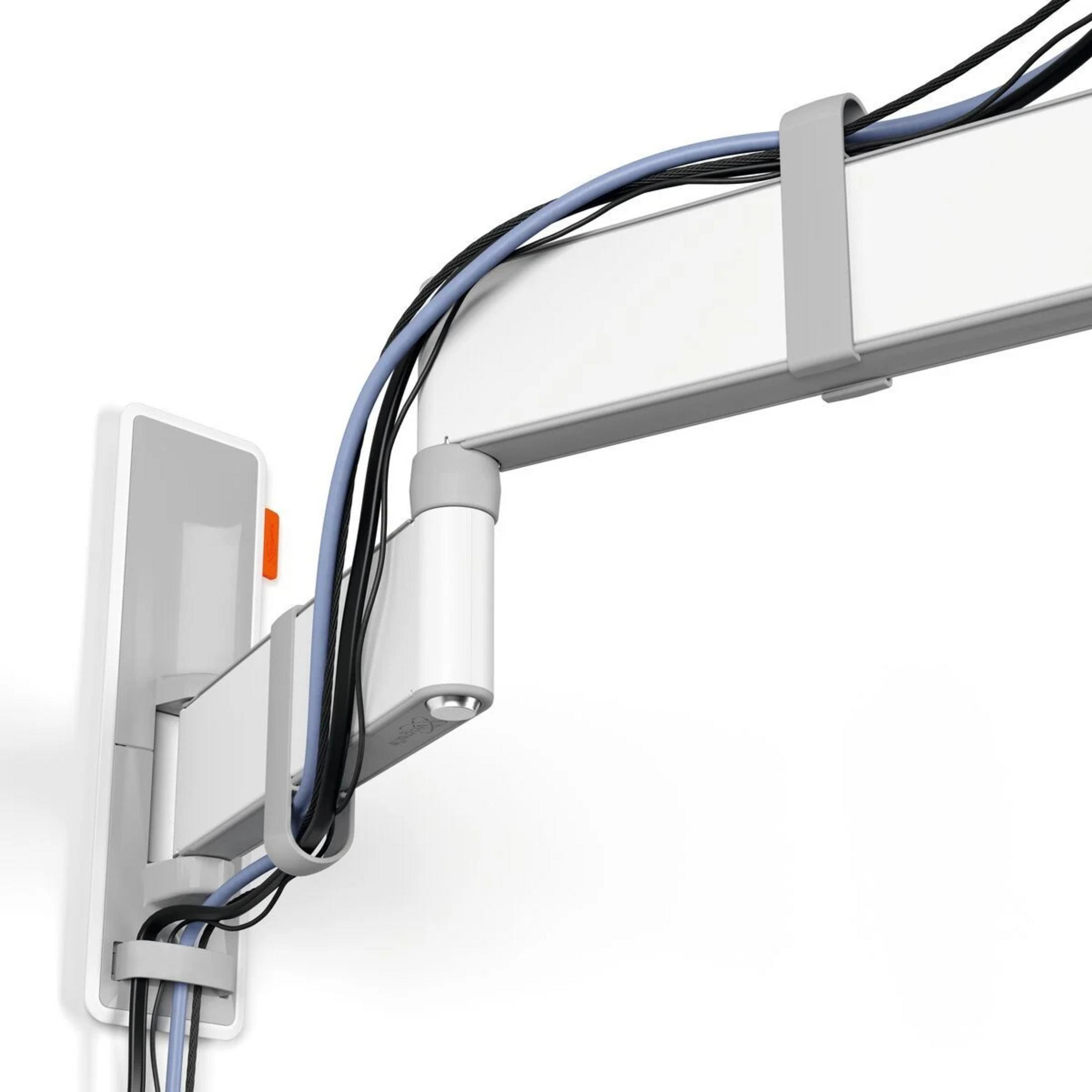 Biały uchwyt na kable na ścianie z czarnymi i niebieskimi kablami.