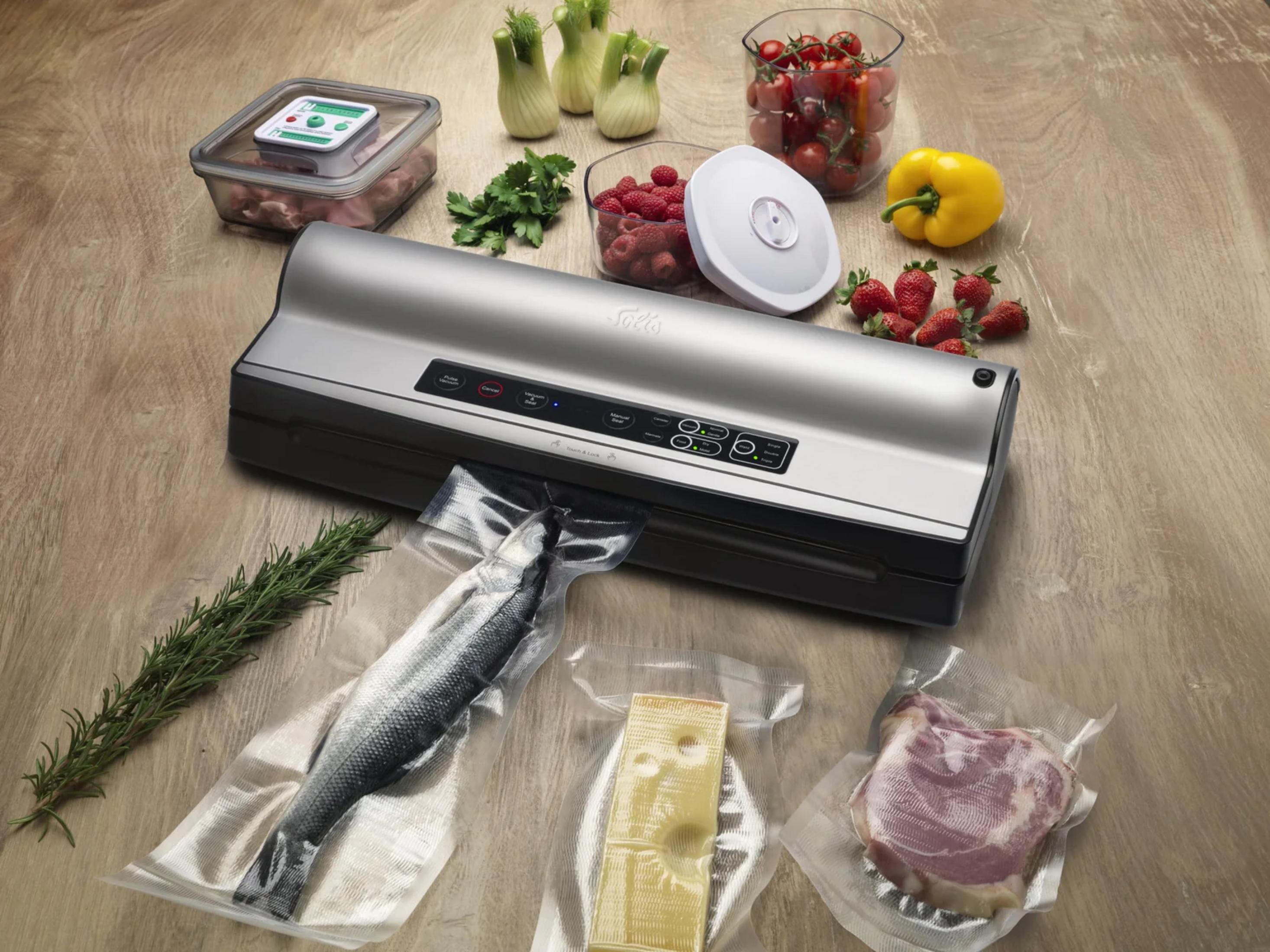 Ein Vakuumierer mit Fisch, Käse, Fleisch, Beeren, Tomaten und gelber Paprika.