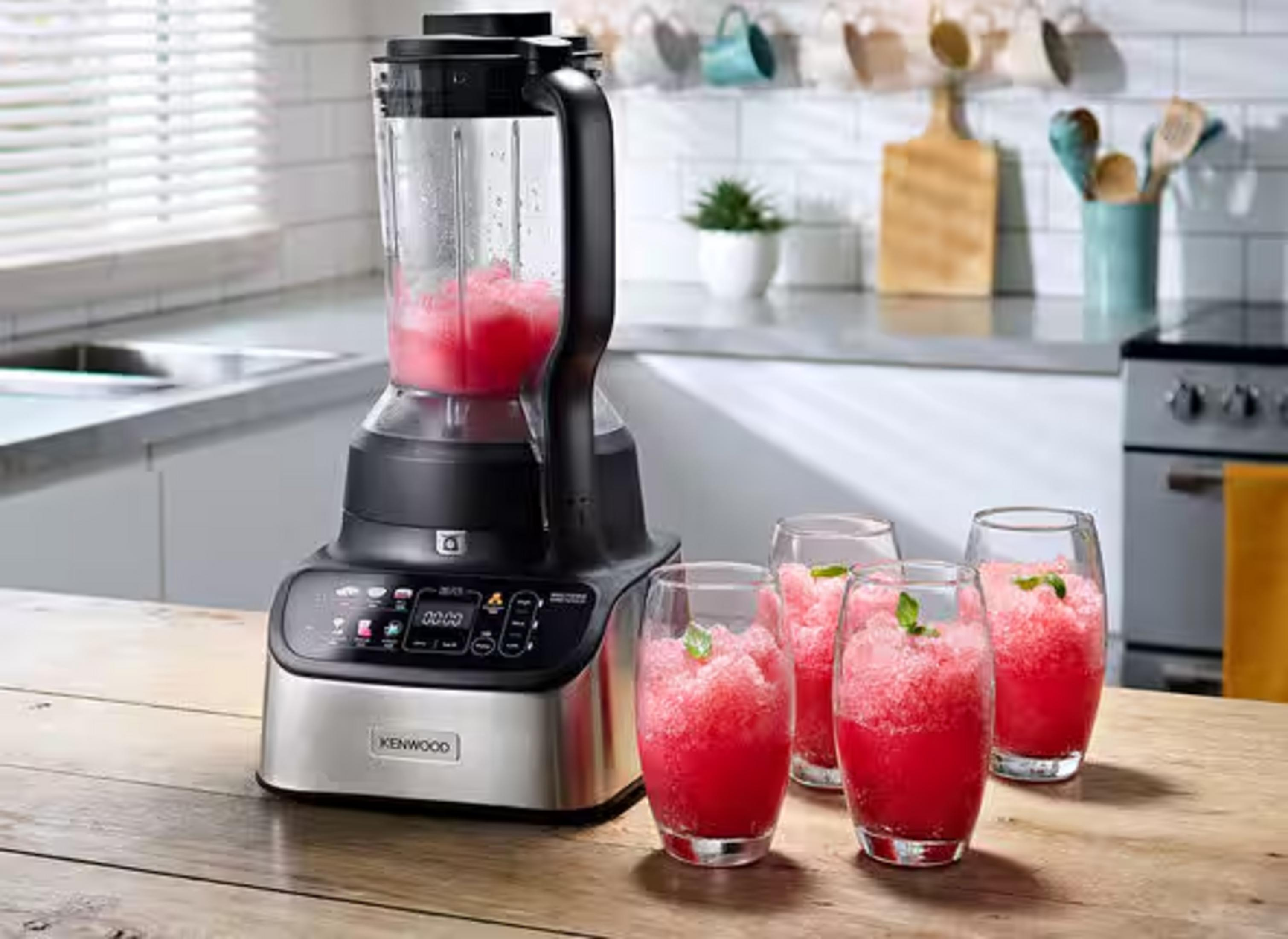 Un frullatore Kenwood con una bevanda granita rossa accanto a quattro bicchieri pieni.