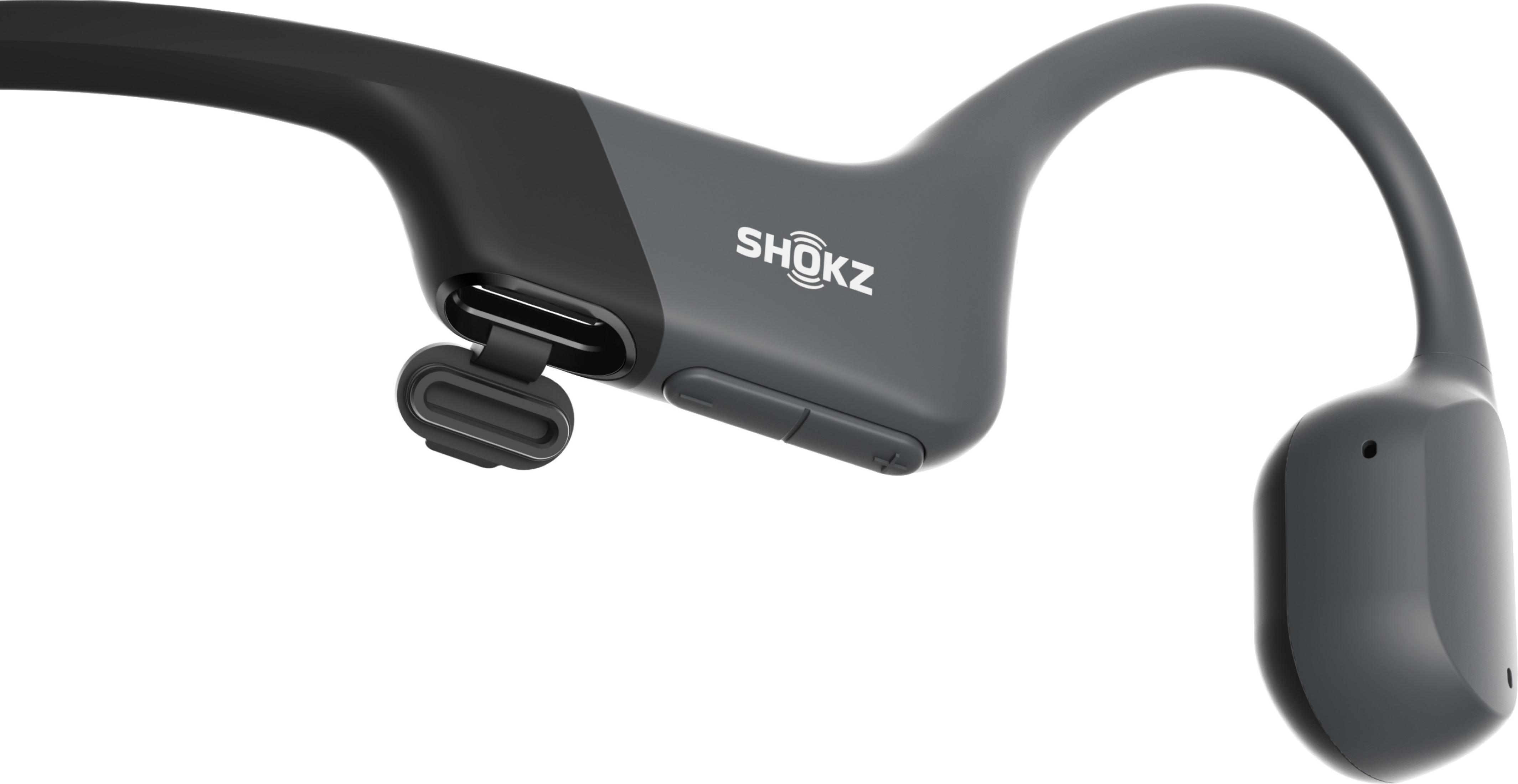 Cuffie SHOKZ a orecchio aperto grigio scuro, porta di ricarica aperta.