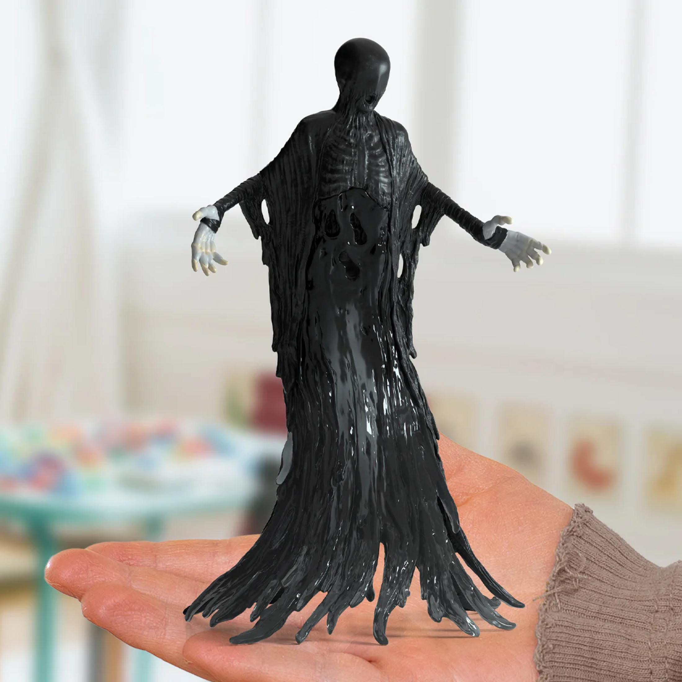 Una figura nera con torso scheletrico è tenuta su una mano.
