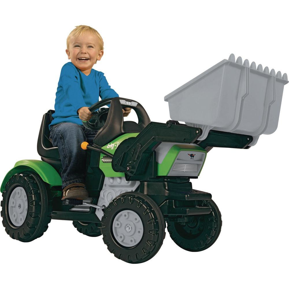 Wesołe dziecko jedzie na zielonym traktorze zabawką z ładowarką.