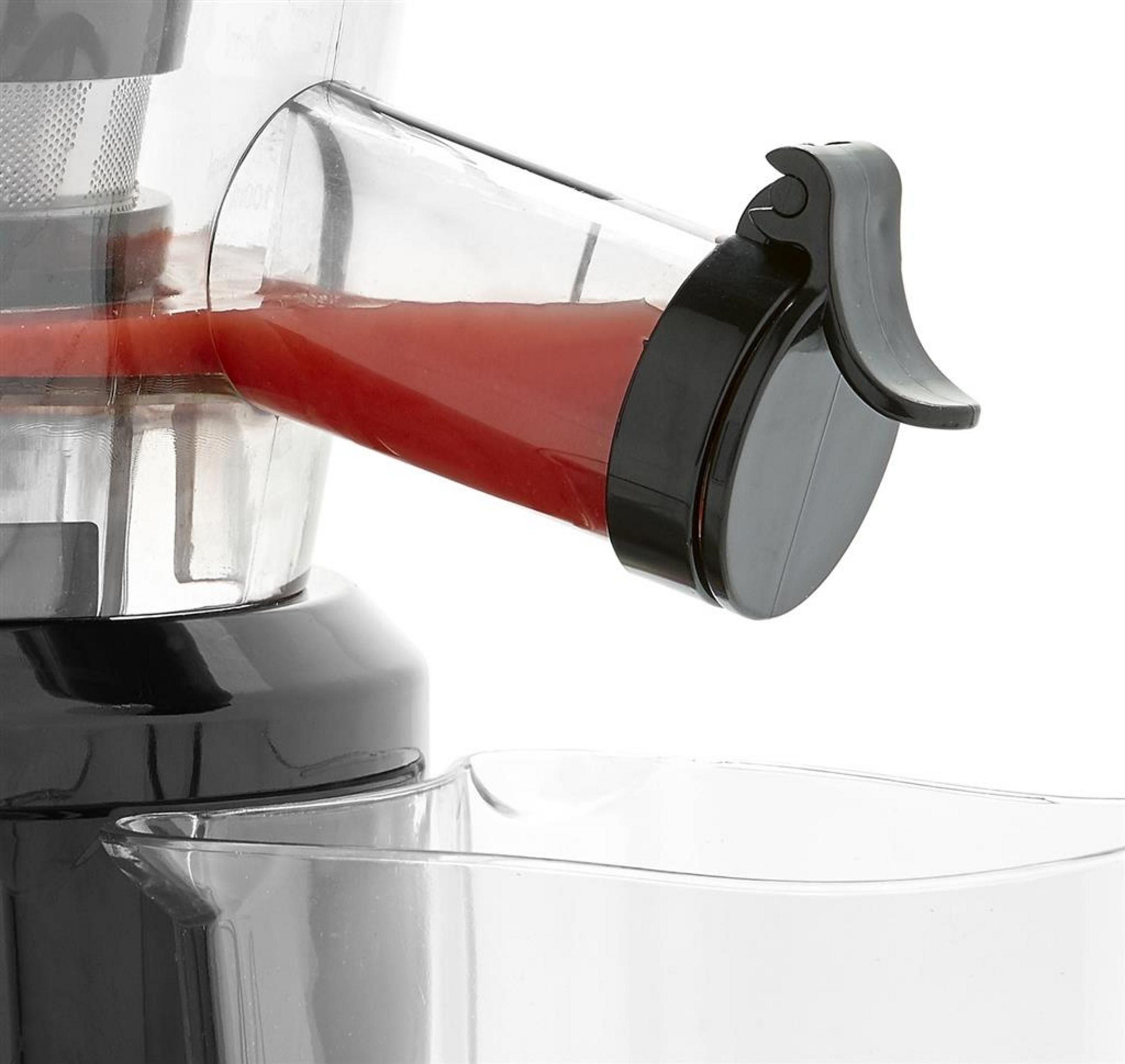 Ein Entsafter mit rotem Saft, der in einen Behälter fließt.