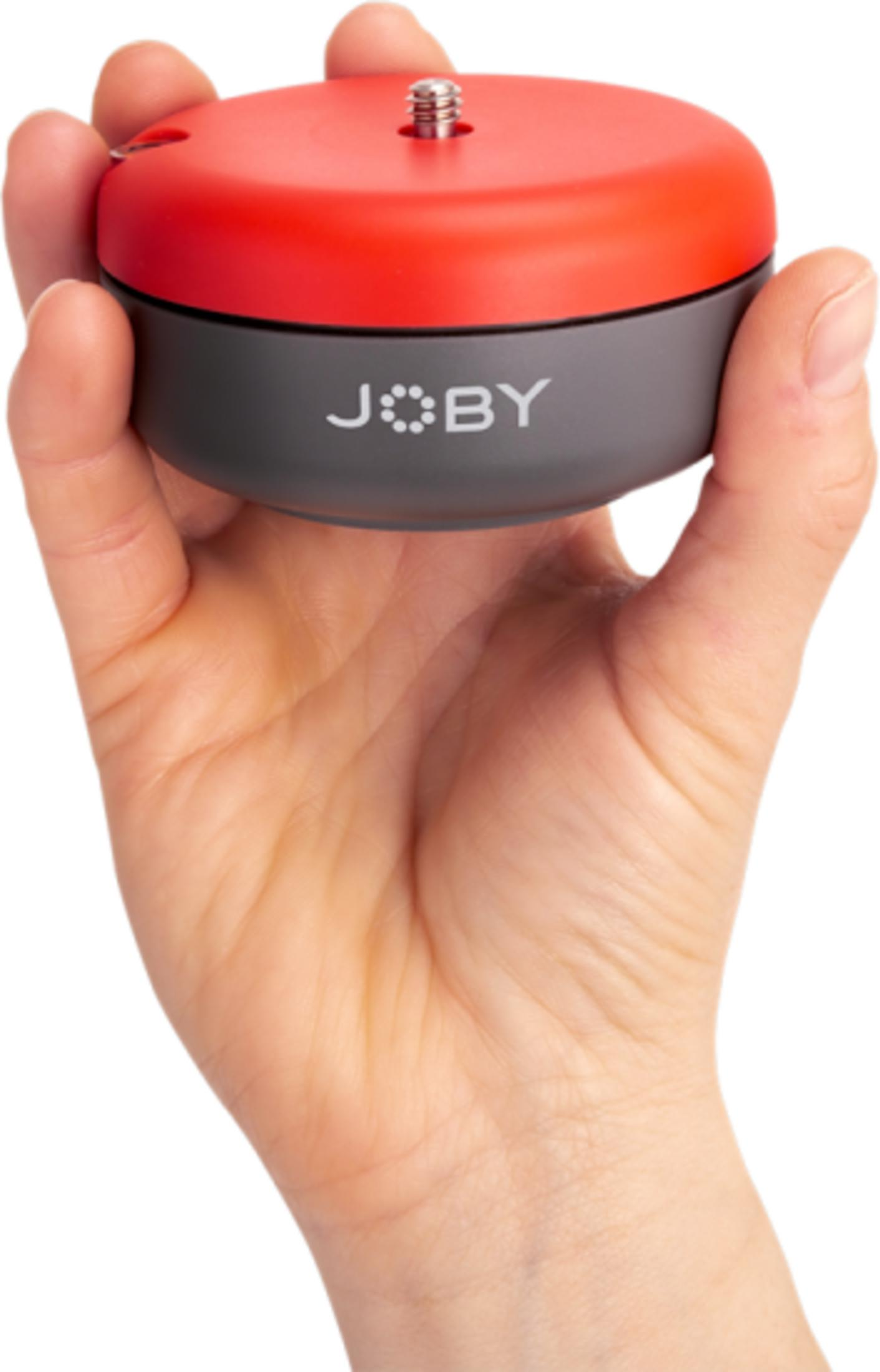 Eine Hand hält ein rotes und graues Joby-Gerät mit einem Gewindebolzen.
