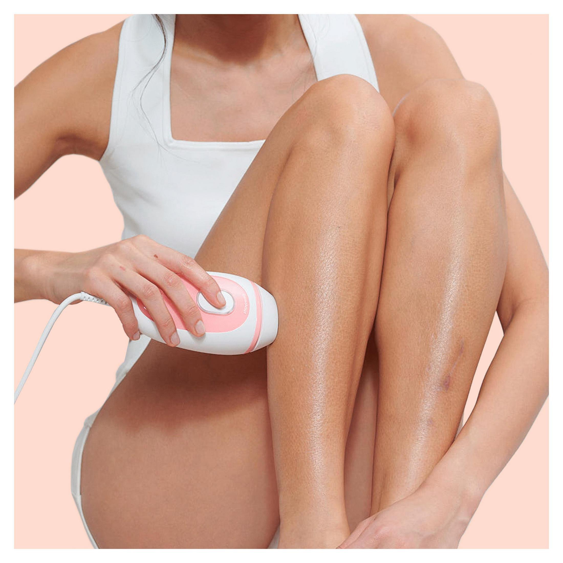 Kobieta używa różowej i białej depilarki na nodze.