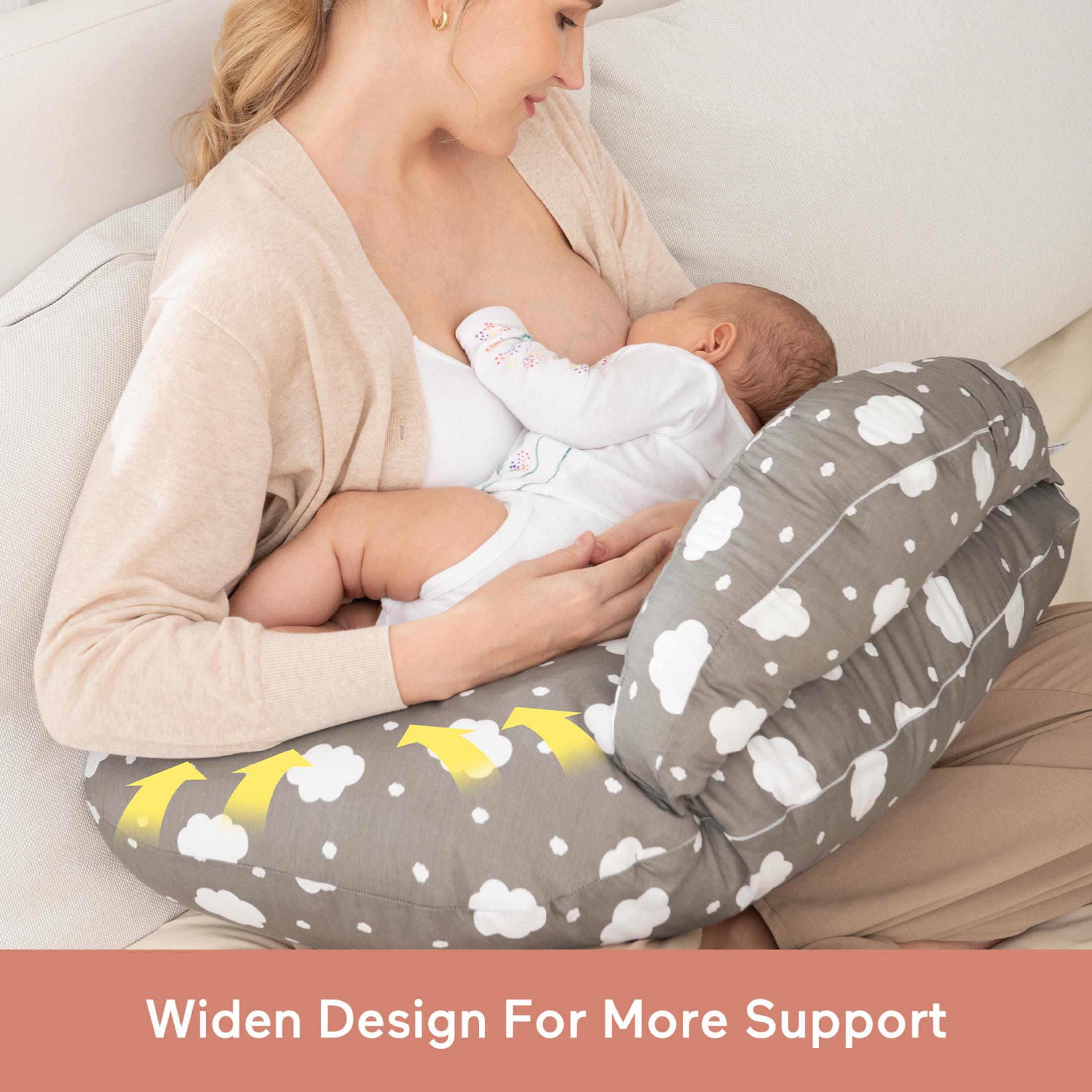 Mutter stillt Baby auf einem Stillkissen mit Wolkenmuster.