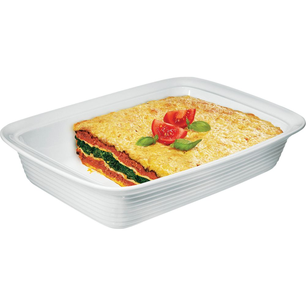 Lasagne in einer weißen Auflaufform mit Tomaten und Basilikum garniert.