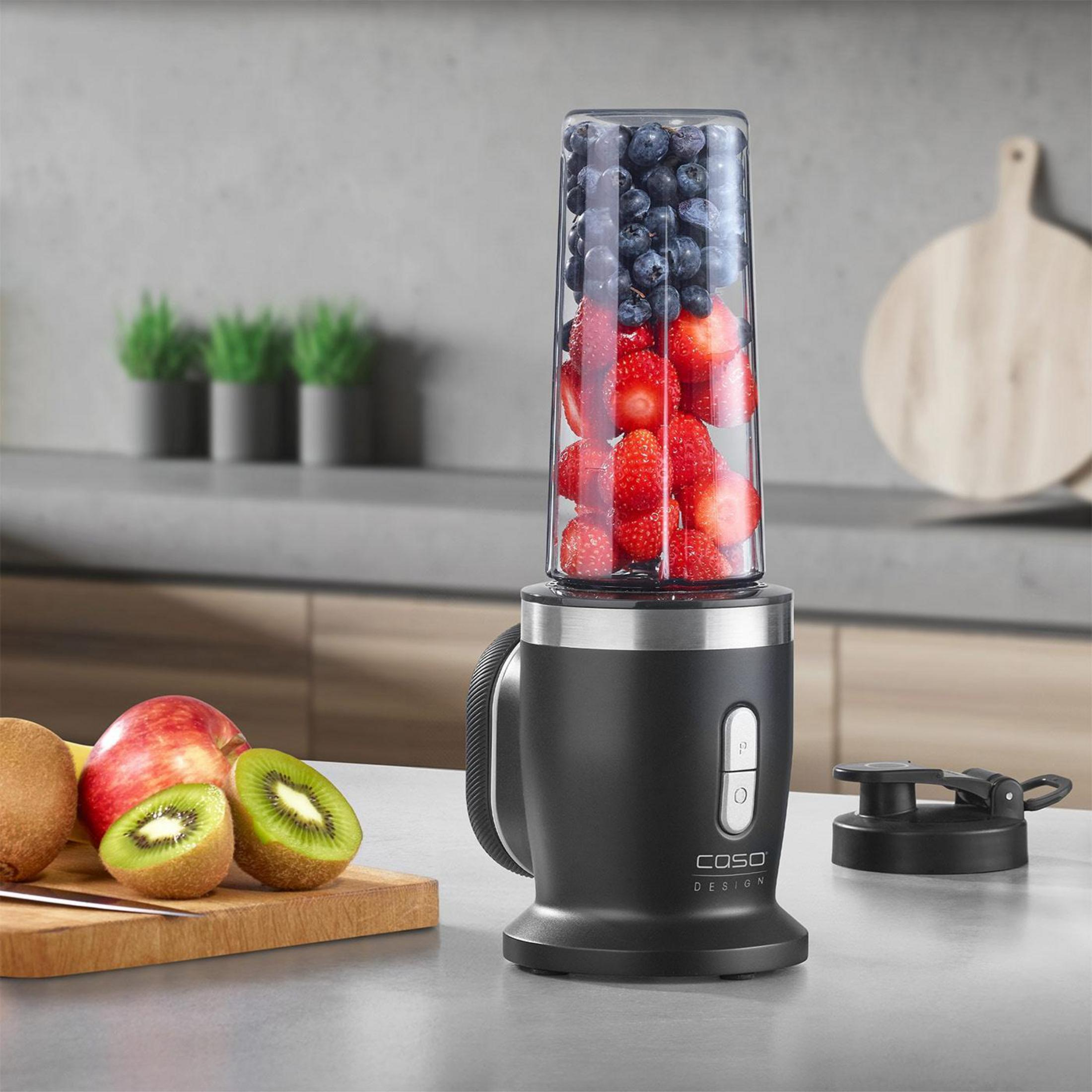 Ein Mixer mit Beeren und Obst auf einem Küchentisch.