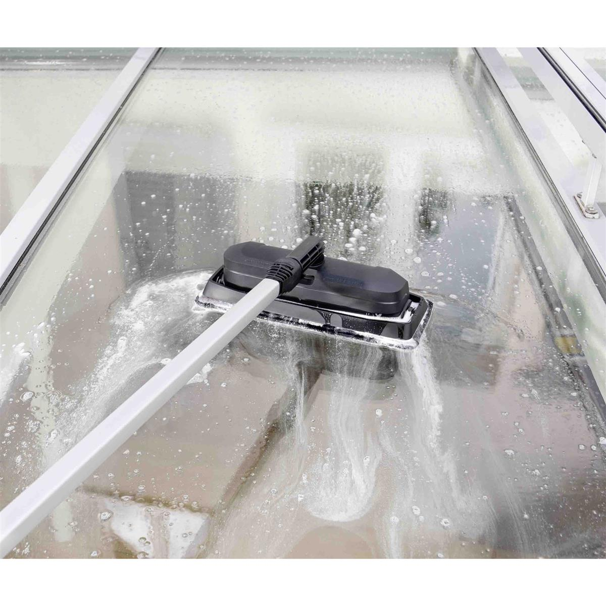 Ein Fensterreiniger mit Stiel reinigt ein nasses Fenster mit Schaum.