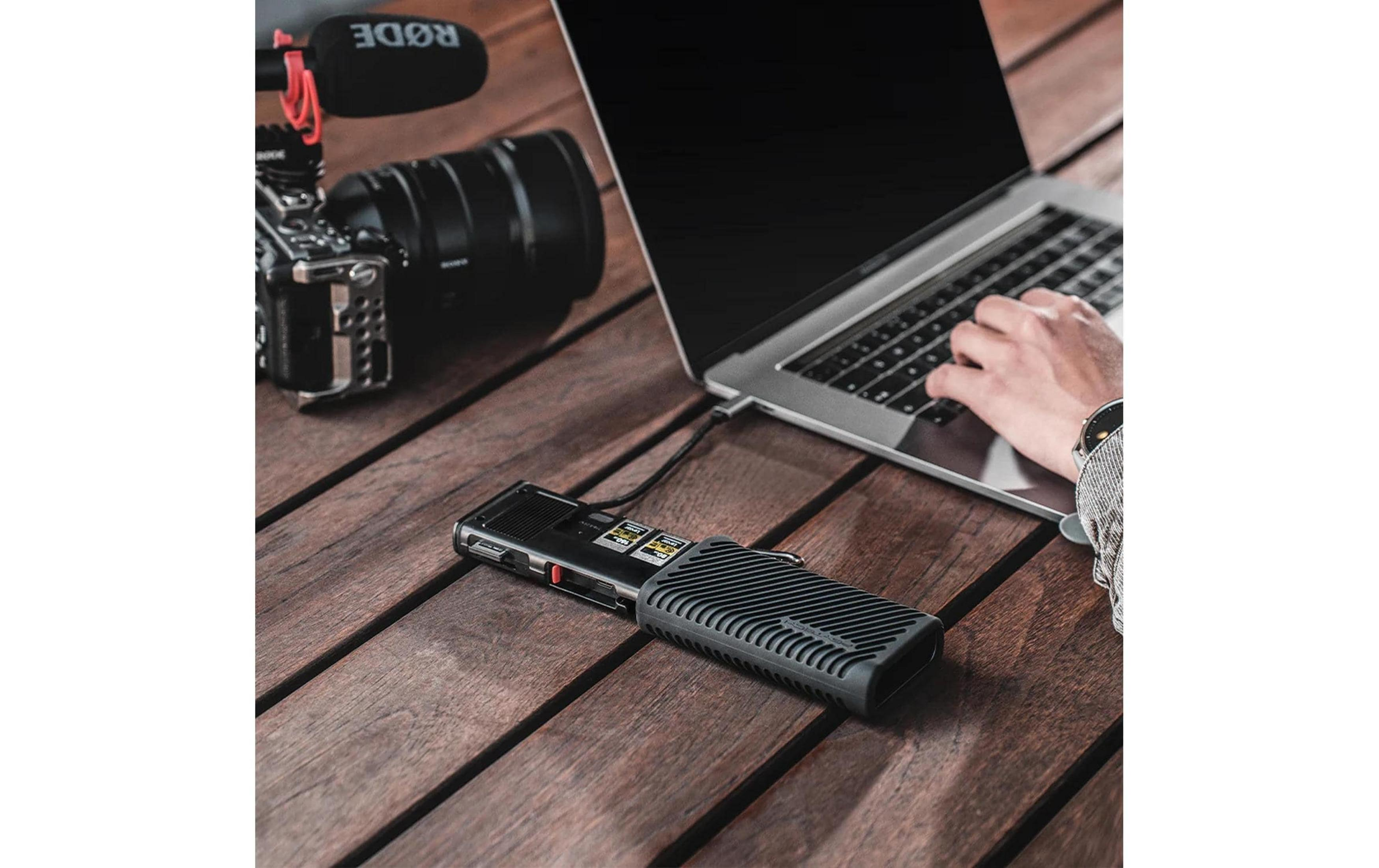 Laptop, aparat z mikrofonem i rejestrator na drewnianym stole.