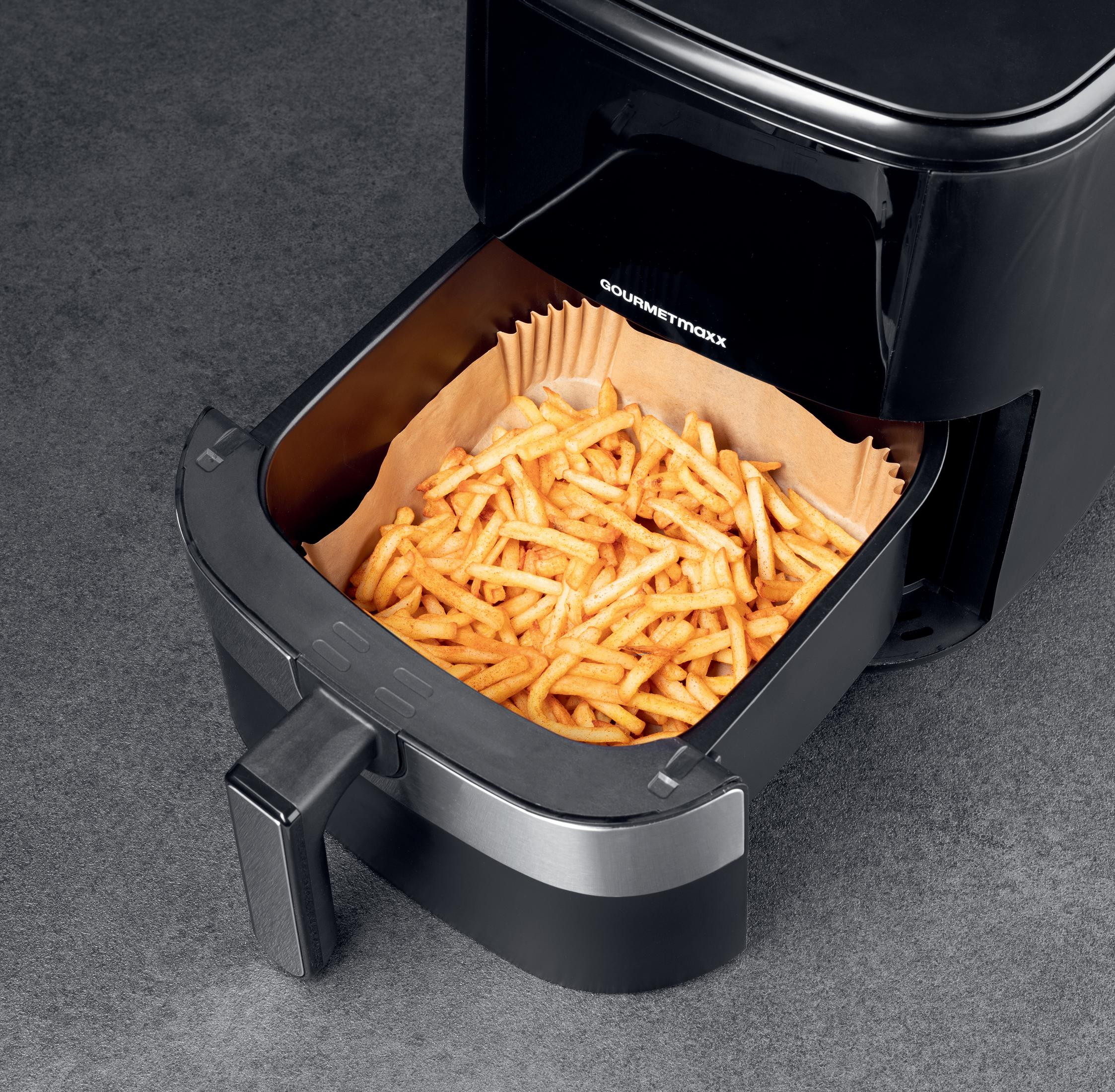 Ein schwarzer Heißluftfritteusenkorb voller goldbrauner Pommes frites auf einer grauen Oberfläche.