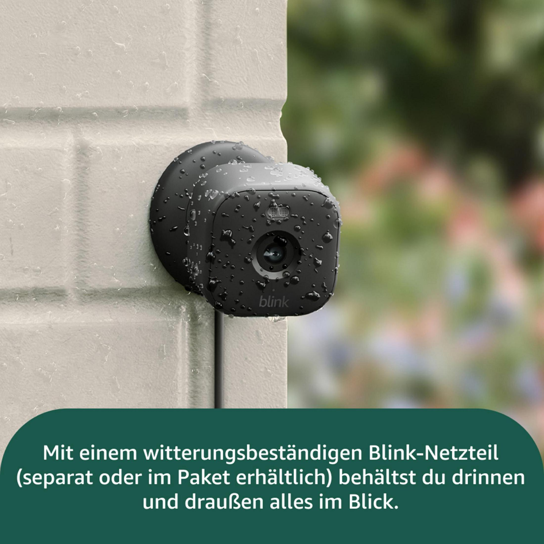 Czarna kamera Blink z kroplami wody na białej ceglanej ścianie.