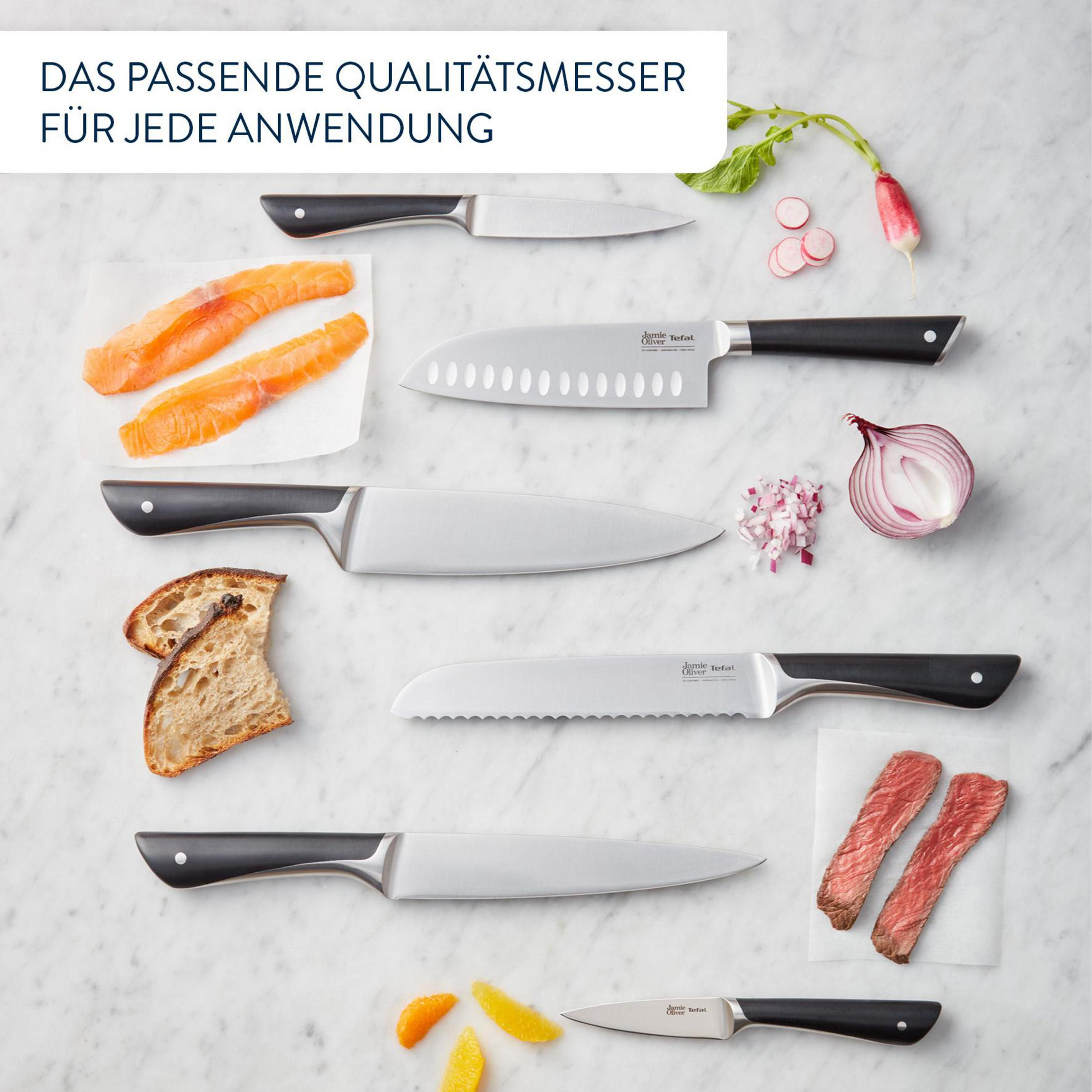 Messer und Lebensmittel auf Marmorplatte. Lachs, Brot, Zwiebeln, Radieschen, Steak.
