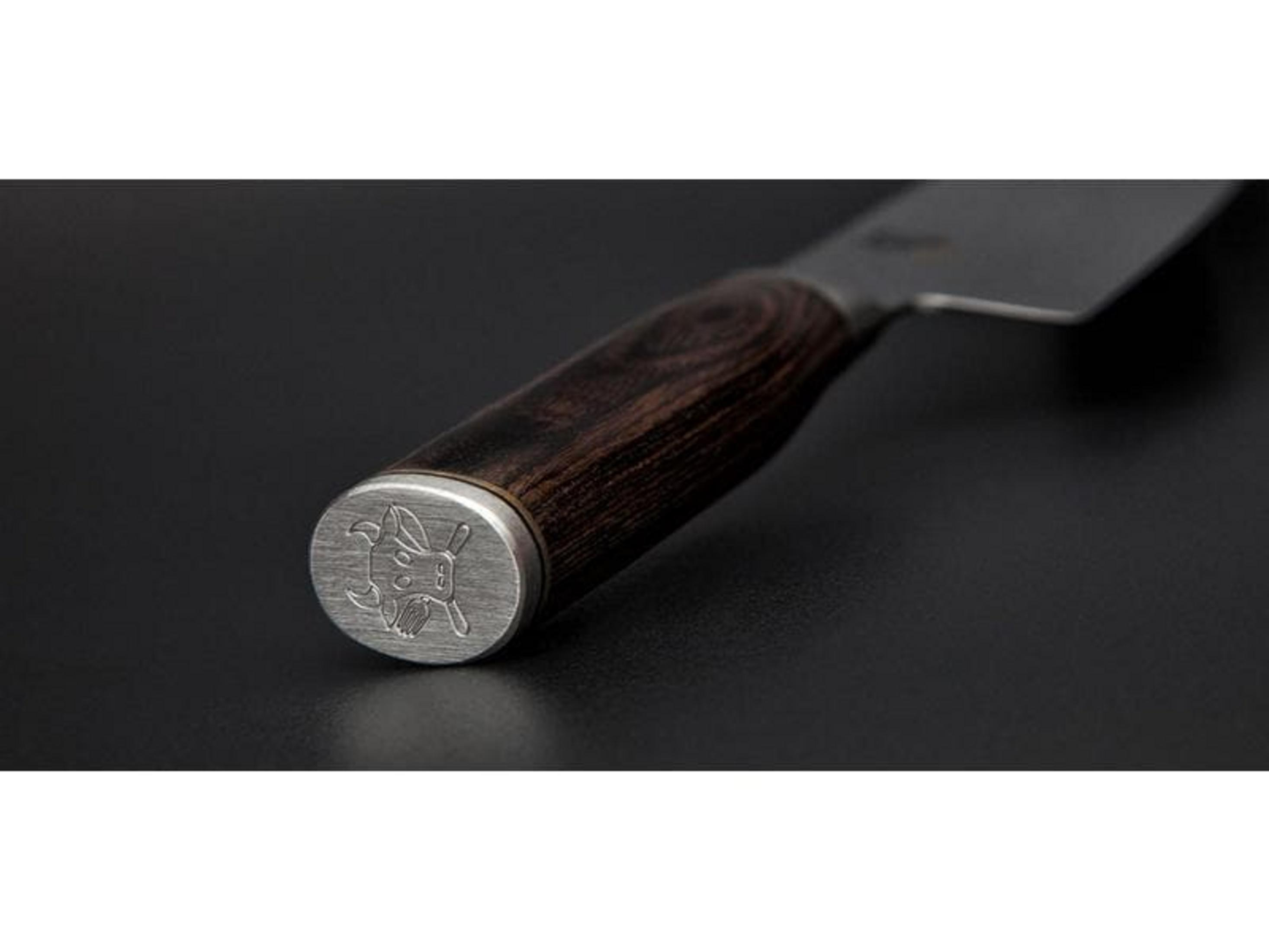 Un mango de cuchillo de madera oscura con un capuchón plateado con un logo de animal.