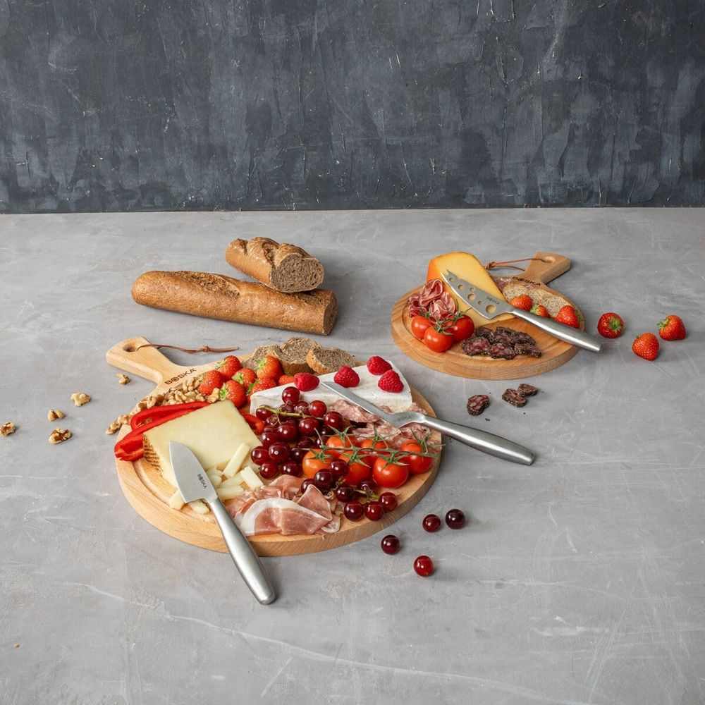 Cheese boards with bread, fruit, vegetables, and charcuterie on wooden platters.