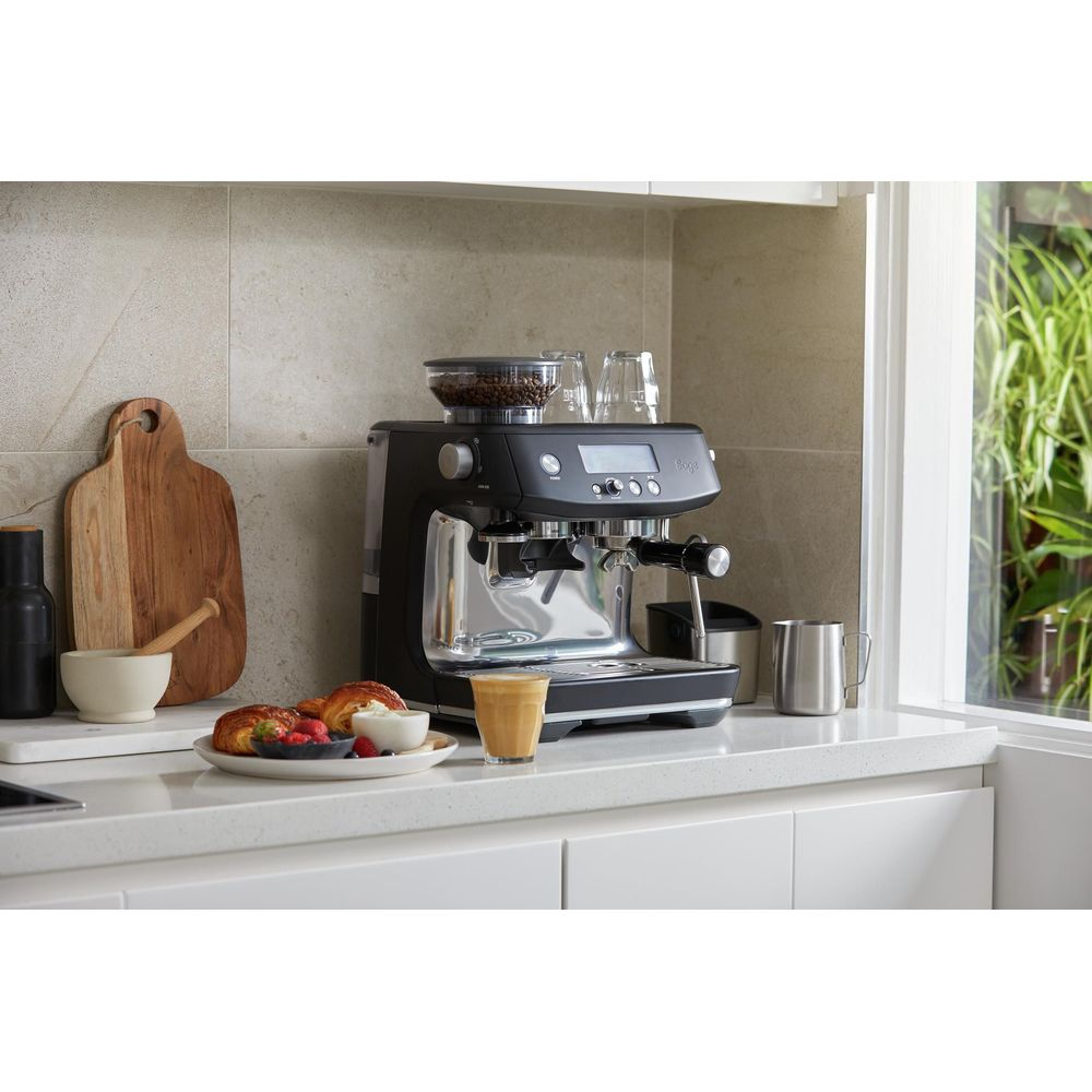Une machine à expresso noire avec des grains de café et des verres sur le dessus.