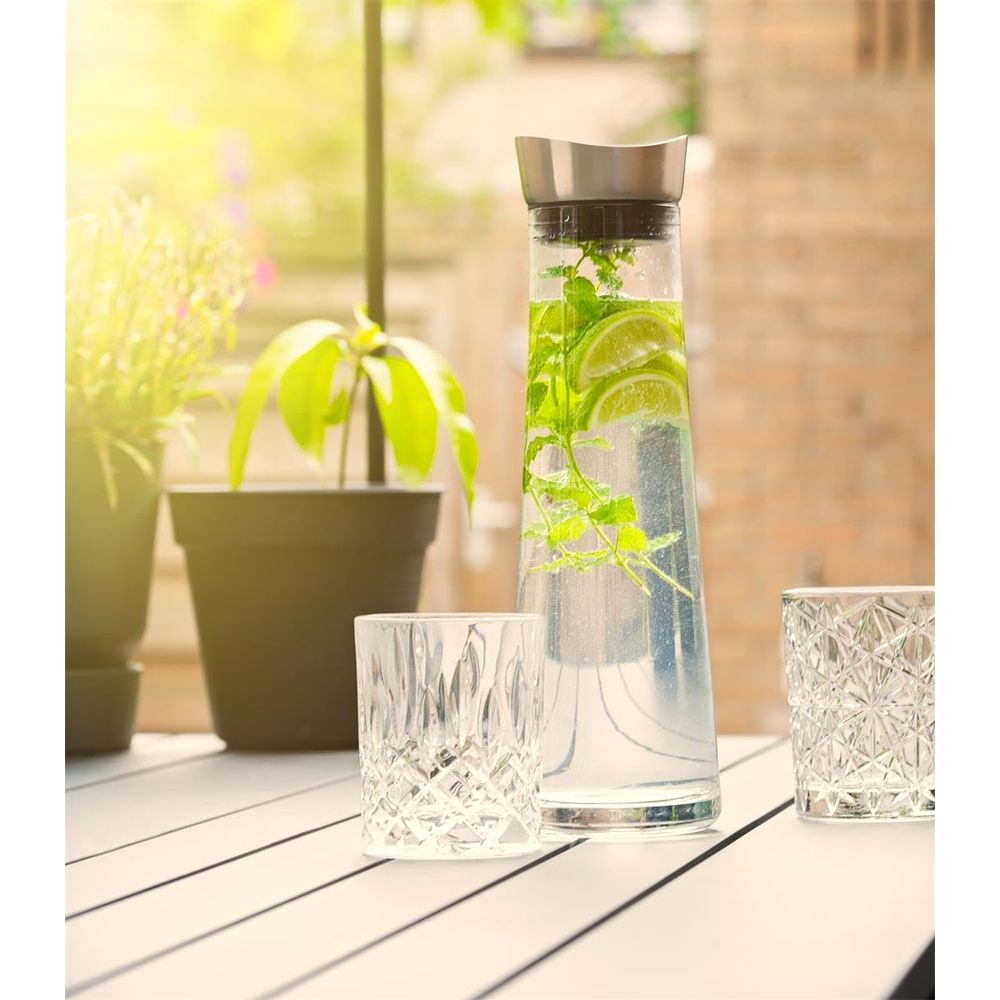 Caraffa con acqua di lime e menta su un tavolo con due bicchieri.