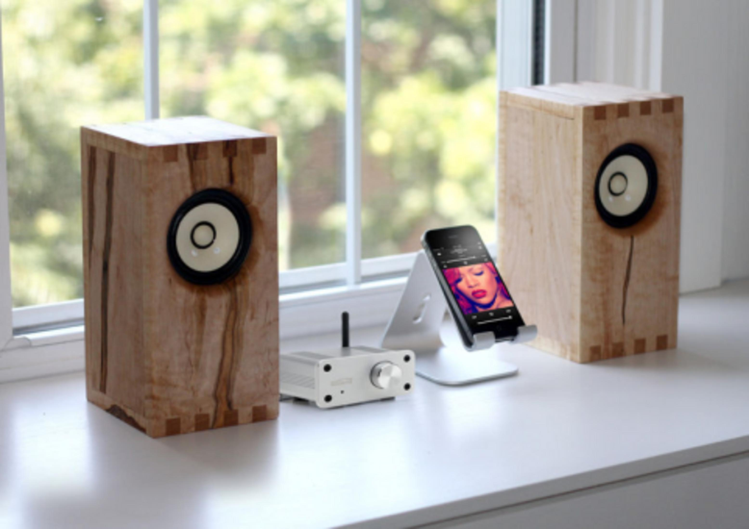Deux haut-parleurs en bois avec un smartphone sur un support et un amplificateur.