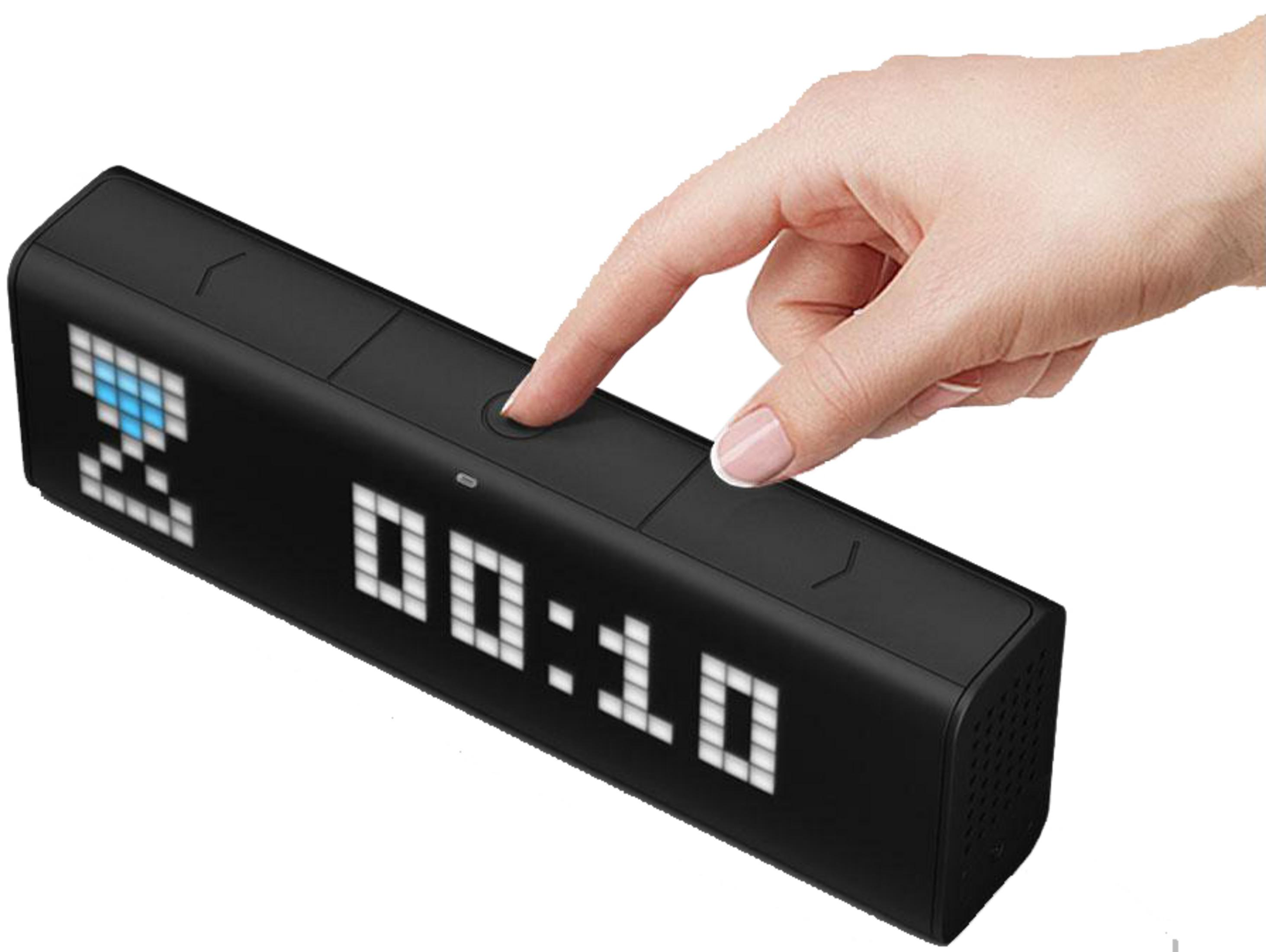 Une main appuie sur un bouton d'un réveil numérique noir affichant 00:10.