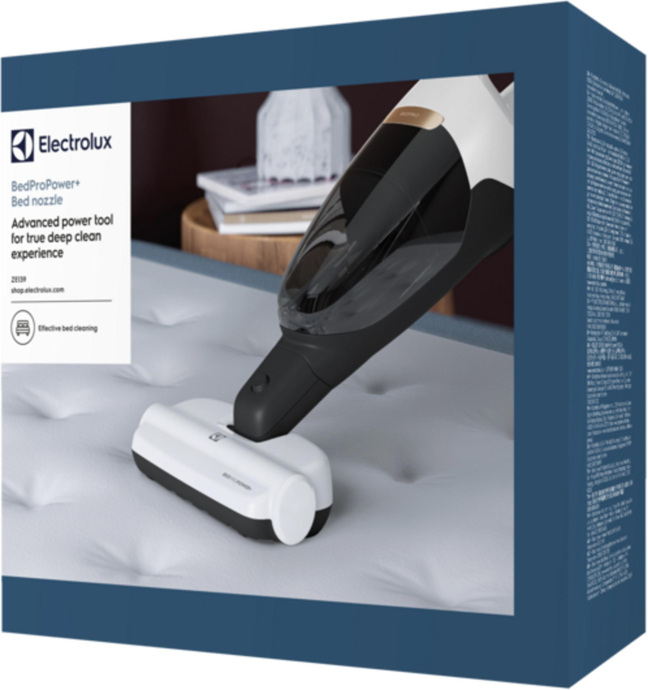 Un aspirateur blanc à main avec manche noir repose sur un matelas.