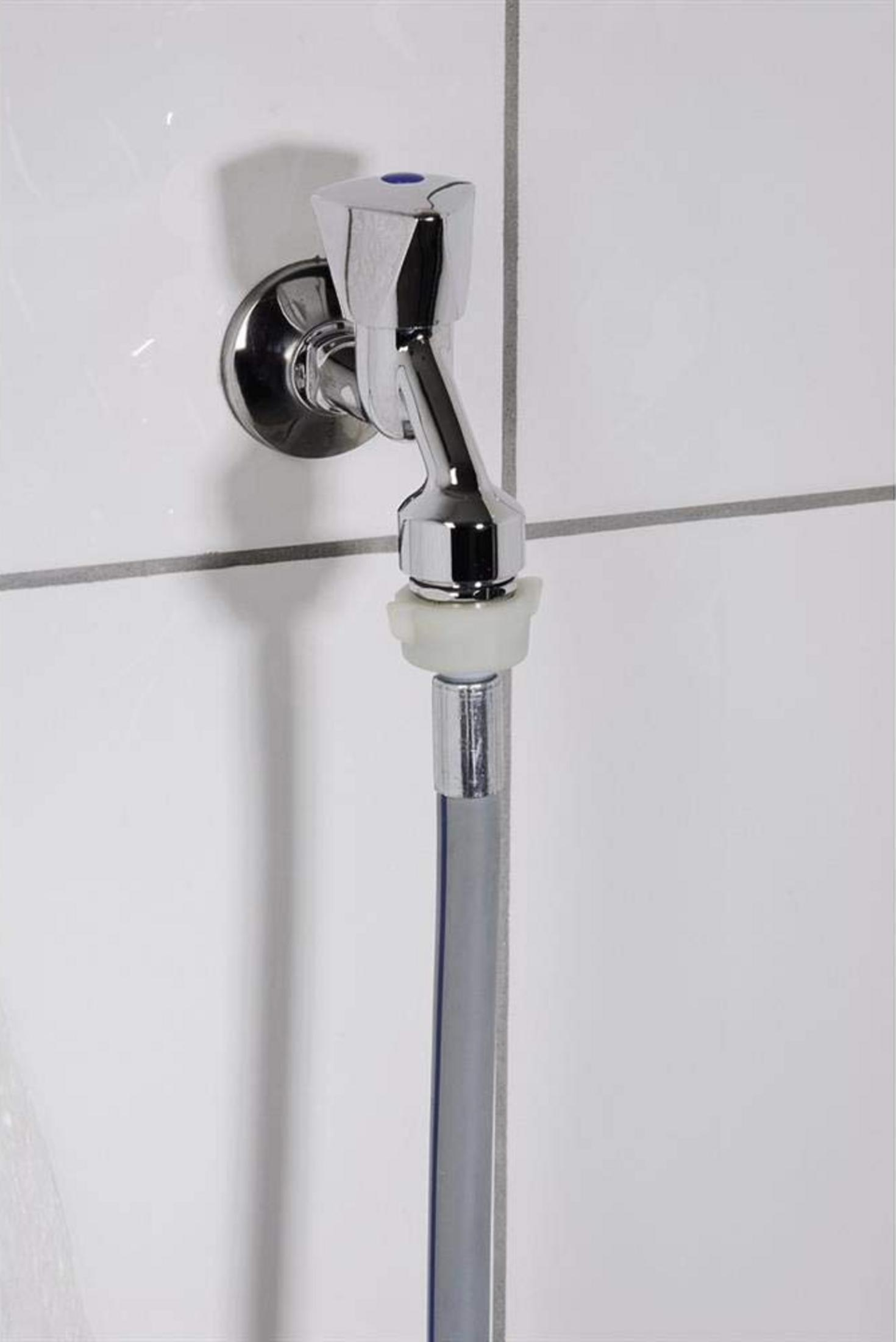 Ein verchromter Wasserhahn mit blauem Knopf an einer weißen Kachelwand.