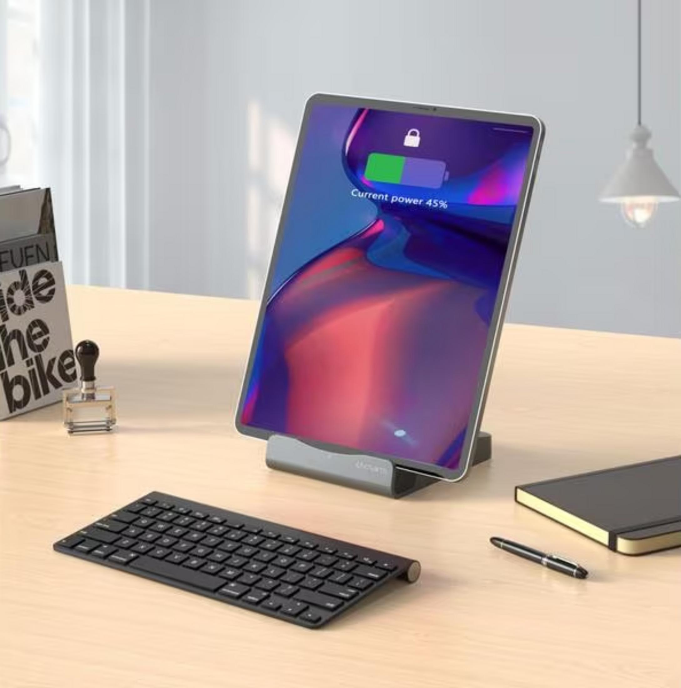 Un tablet su un supporto, con tastiera, taccuino e penna.