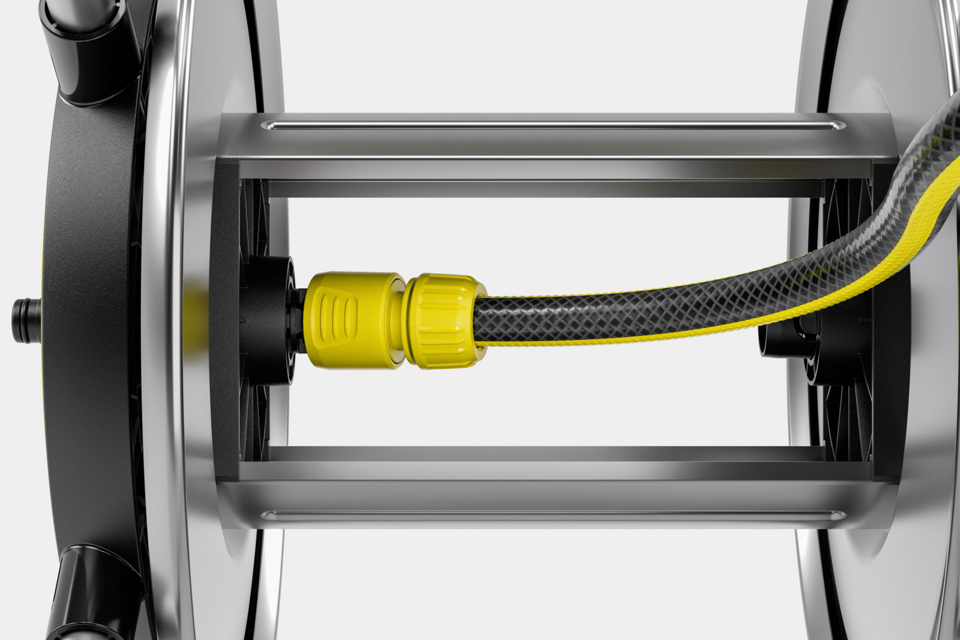 Czarny wąż ogrodowy z żółtymi paskami jest przymocowany do czarno-srebrnej zwijarki węża.