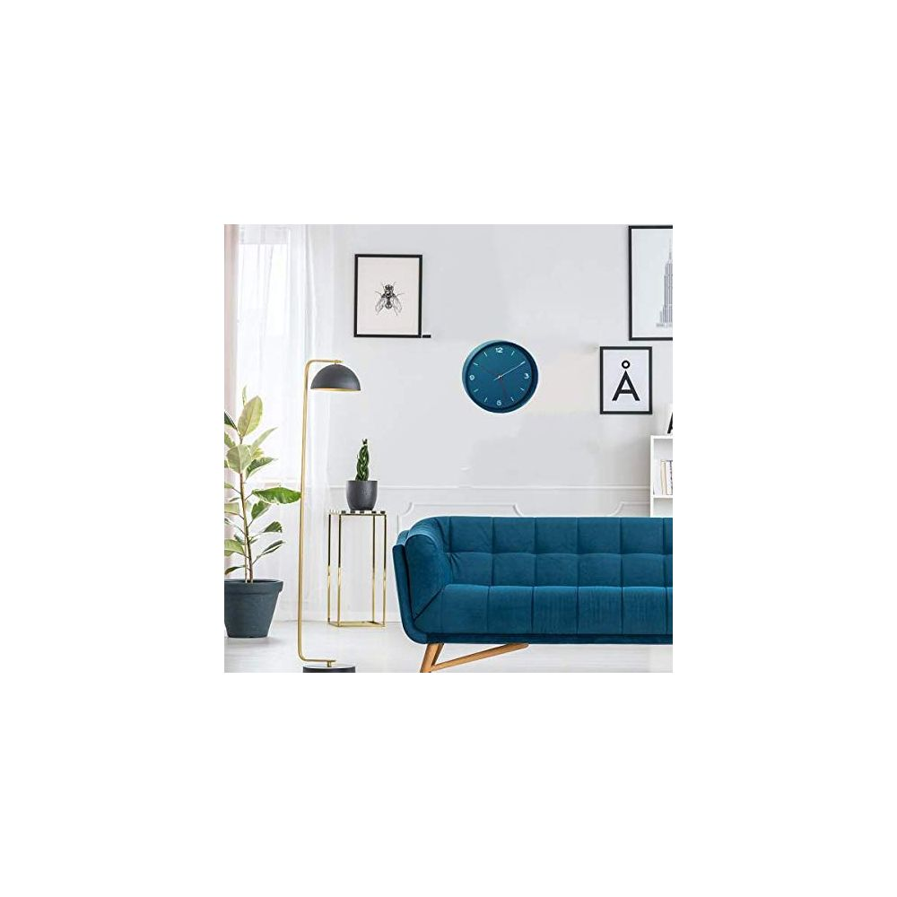 Ein blaues Sofa steht vor einer weißen Wand mit Bildern und einer Uhr.