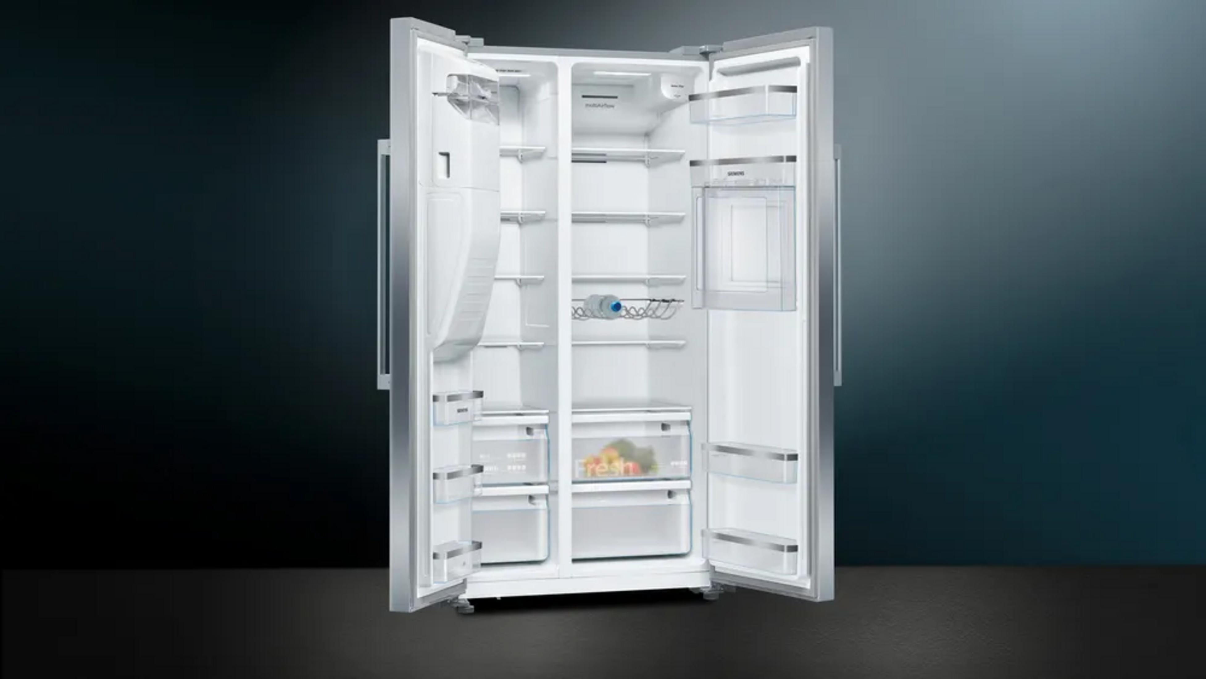 Ein offener silberner Kühlschrank mit zwei Türen, innen leer bis auf einige Fächer und eine Flasche.