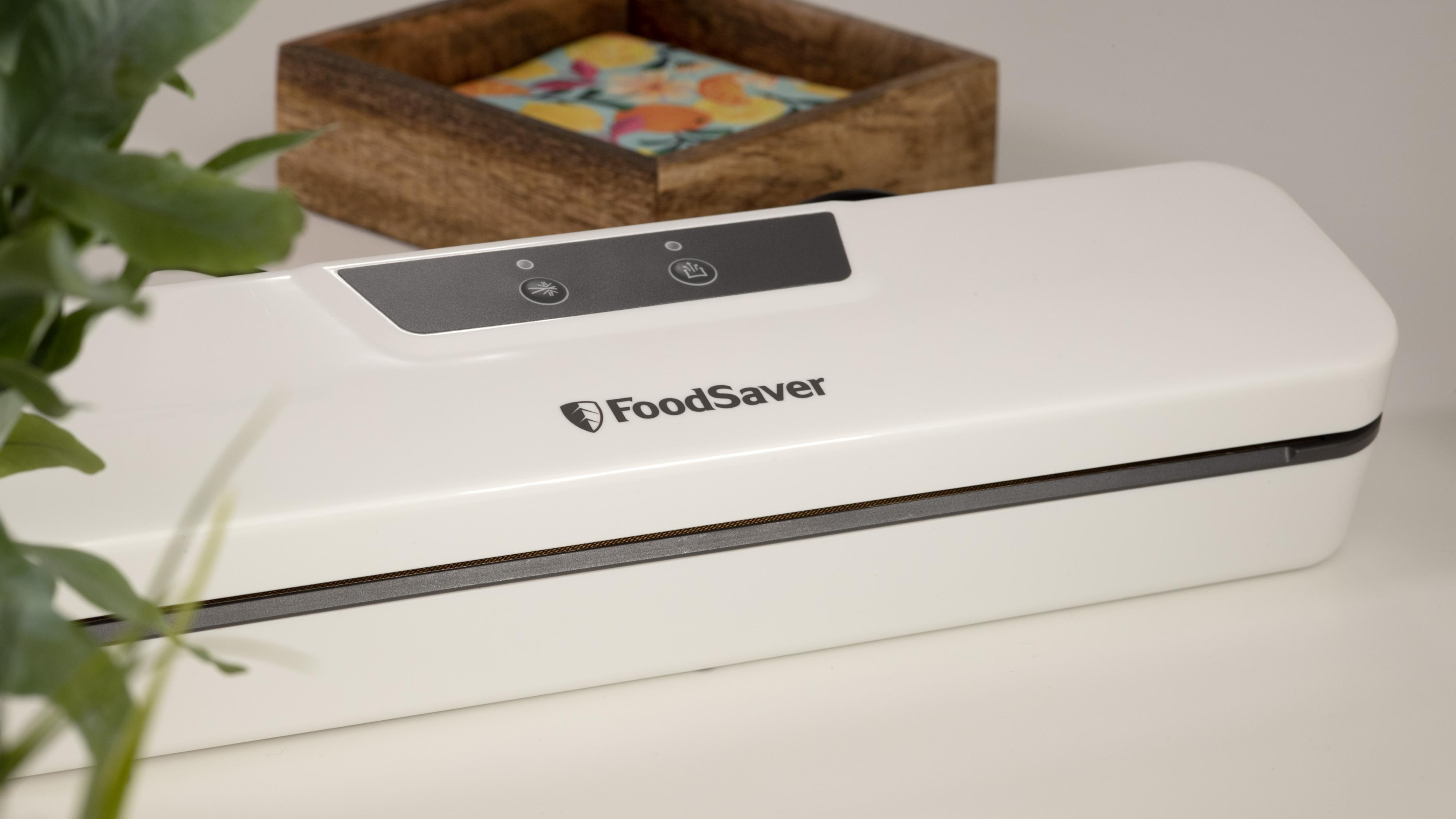 Biała zgrzewarka FoodSaver na stole. W tle drewniane pudełko.