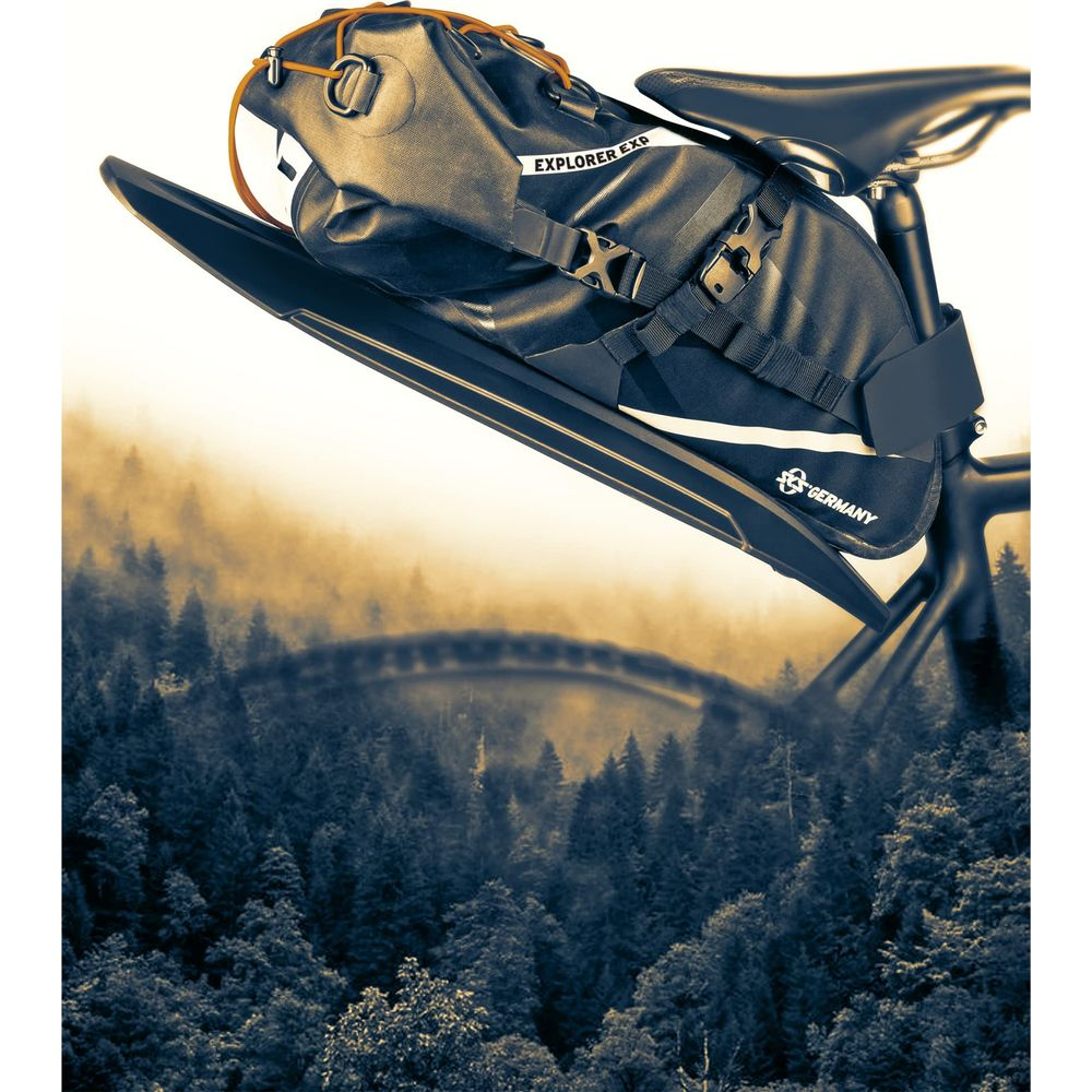 Sacoche de vélo noire avec inscription "EXPLORER EXP" sur forêt et pont embrumés.