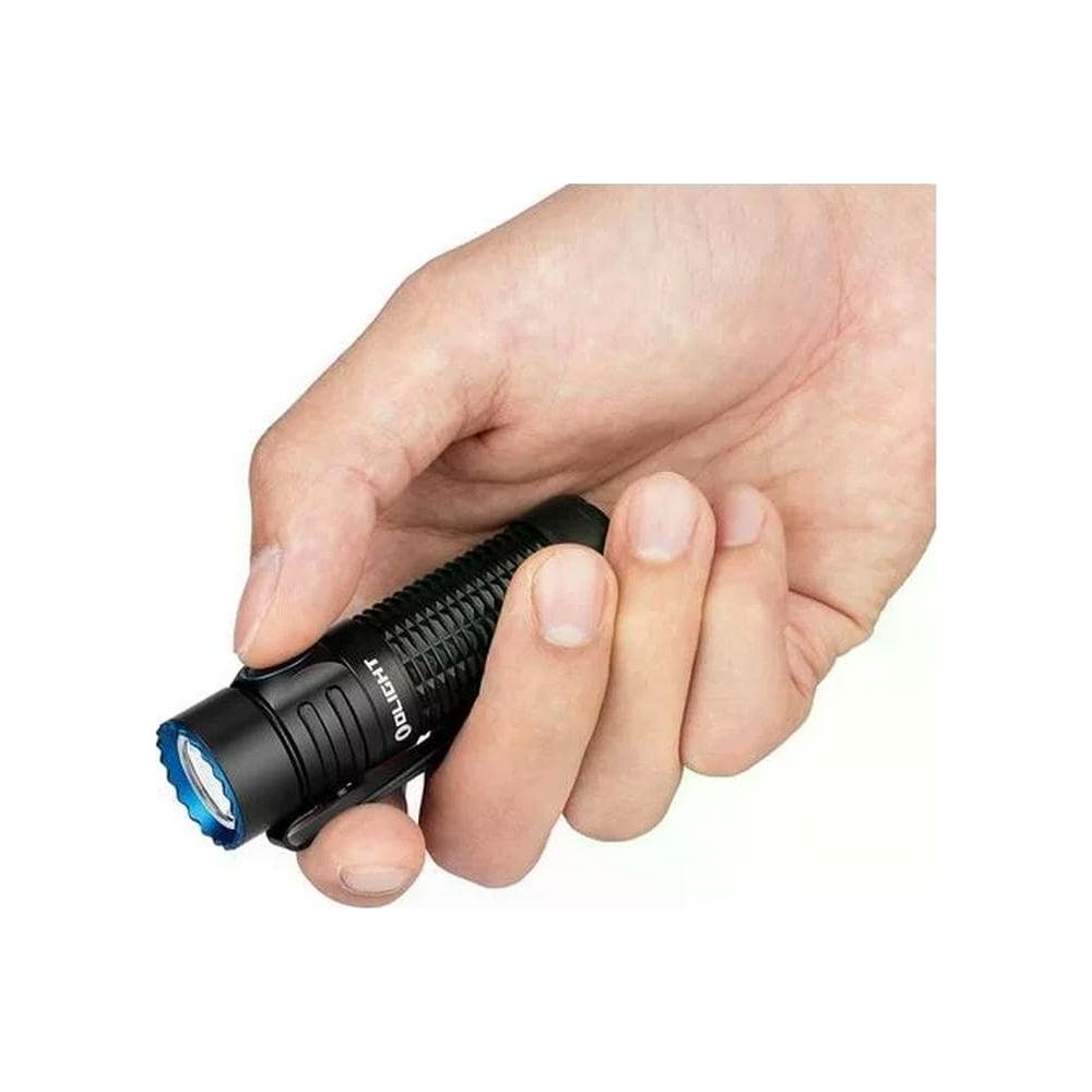 Une main tient une petite lampe de poche noire émettant une lumière bleue.
