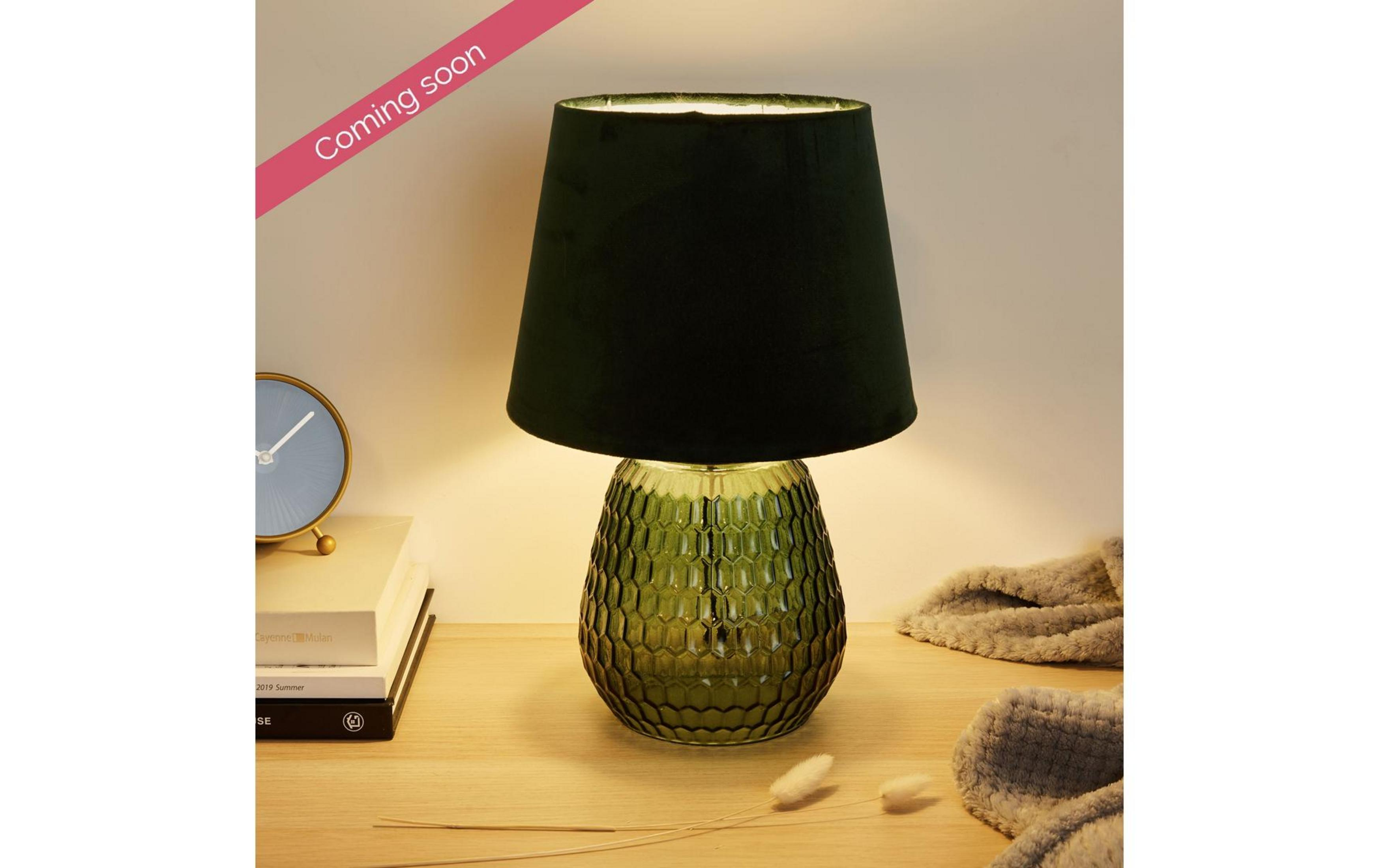 Zielona lampa z teksturowaną podstawą i ciemnym kloszem na drewnianym biurku.