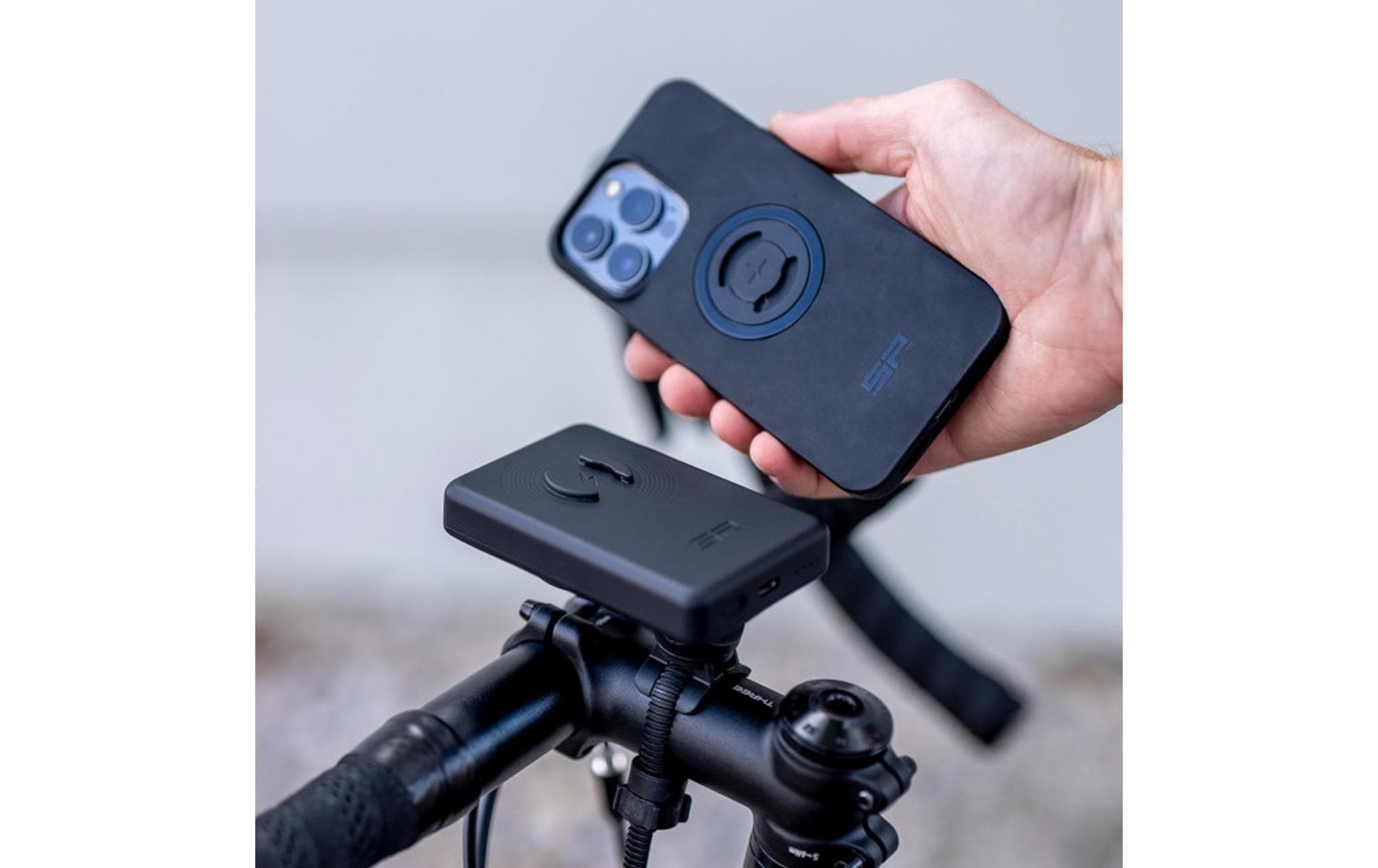 Una mano tiene un telefono nero sopra un supporto da bicicletta nero.