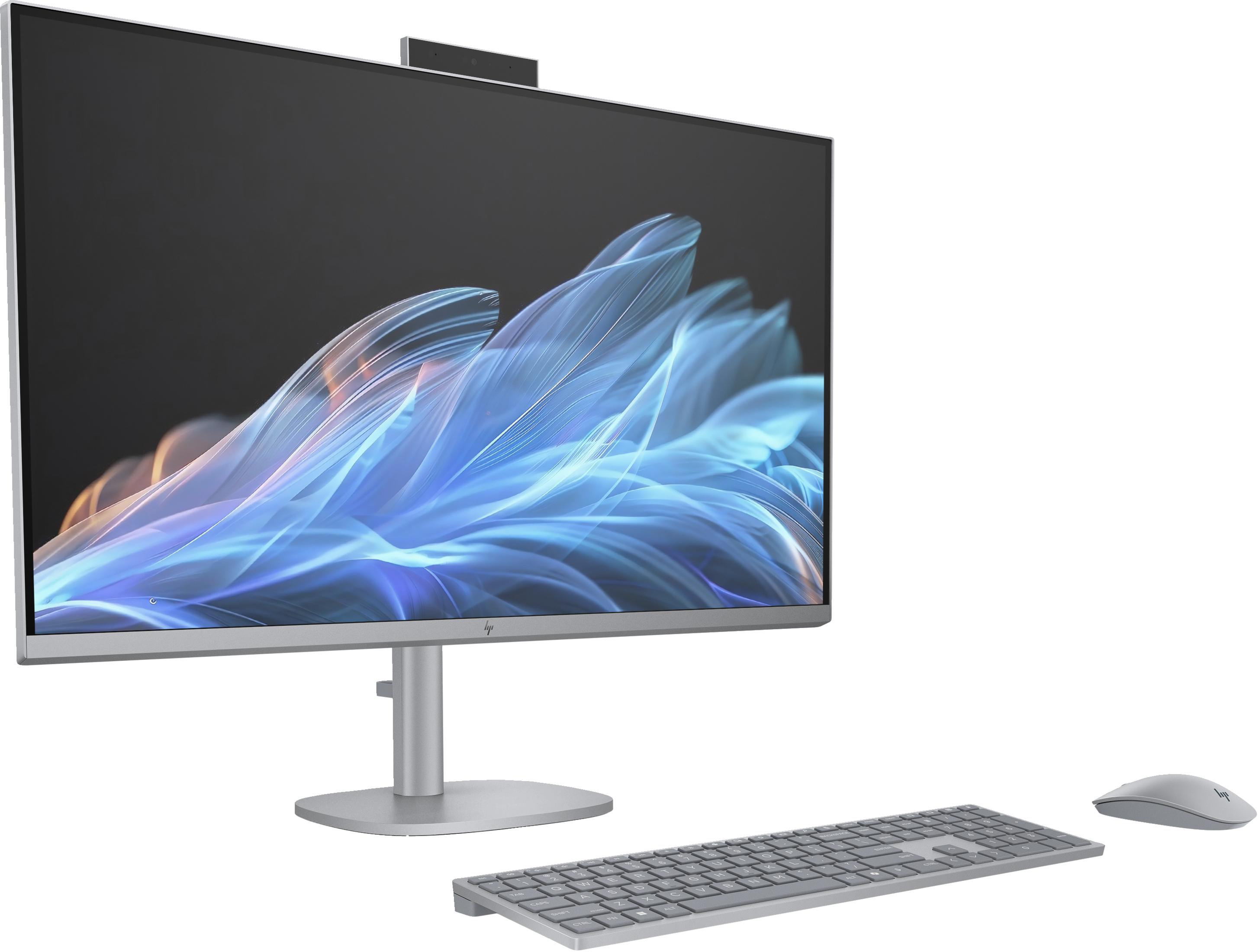Un PC tout-en-un argenté avec clavier et souris sur fond gris.