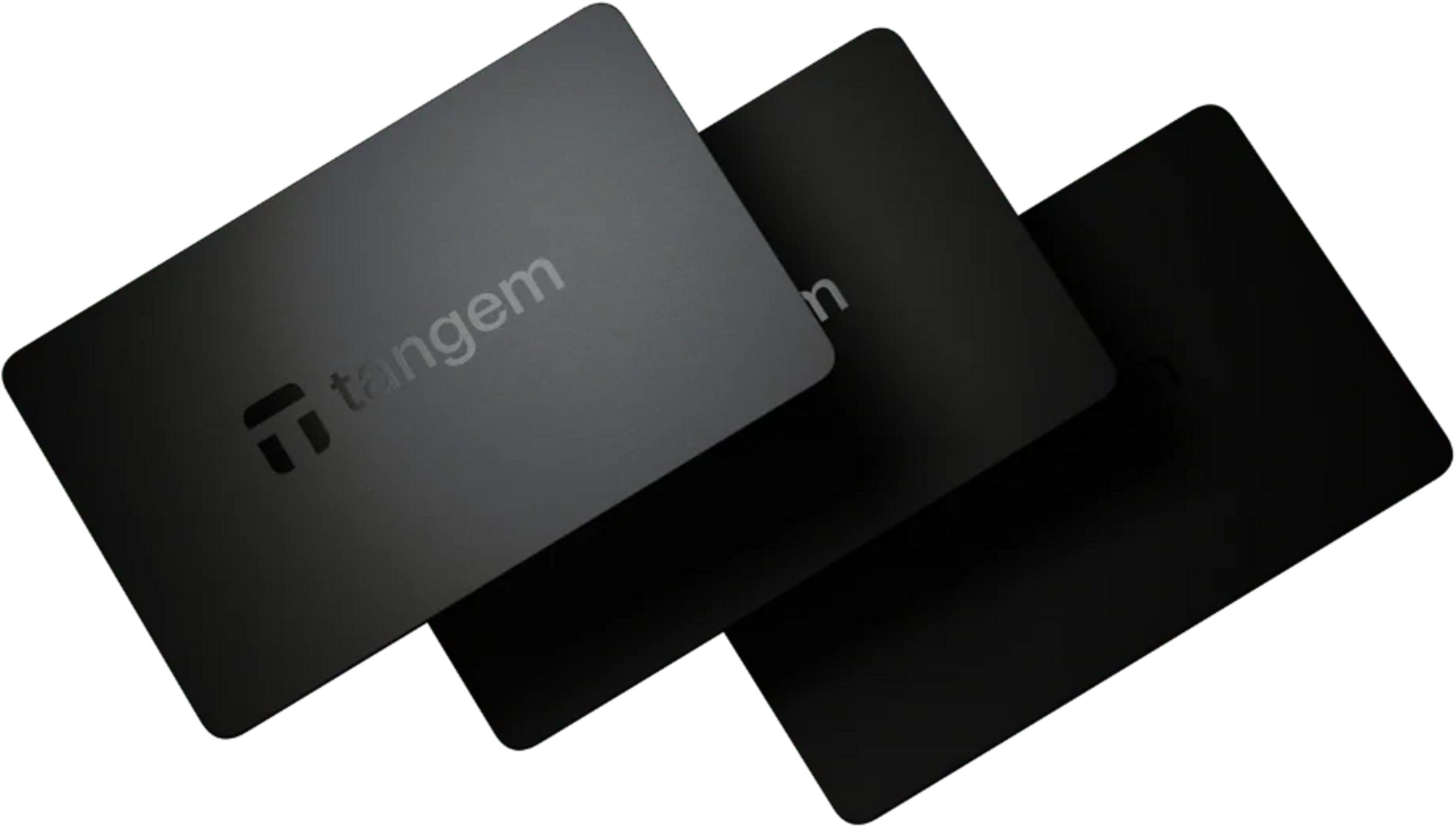 Trzy czarne karty z logo Tangem ułożone warstwowo na białym tle.