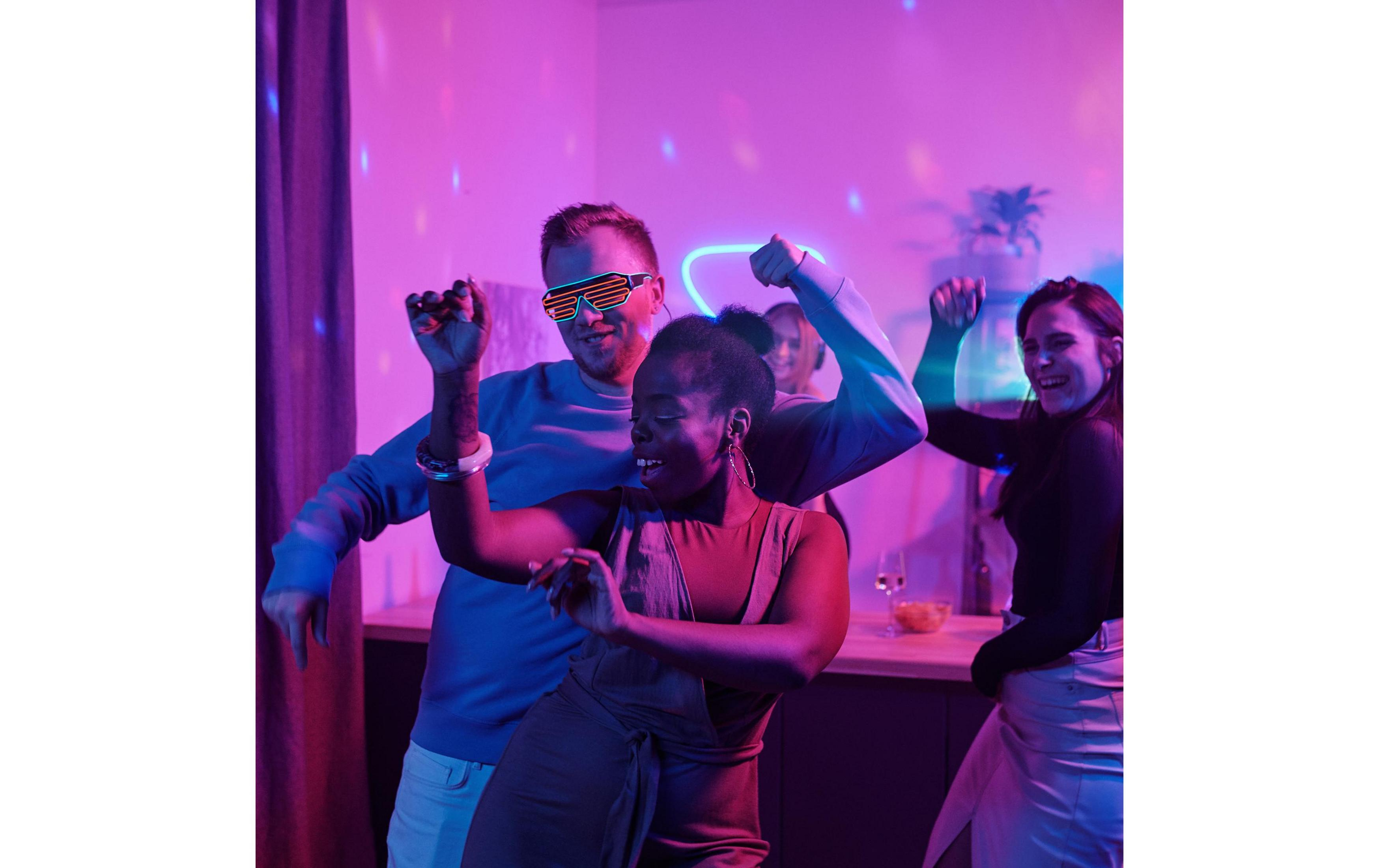 Leute tanzen bei einer Party mit Neonlicht und Lichterketten.