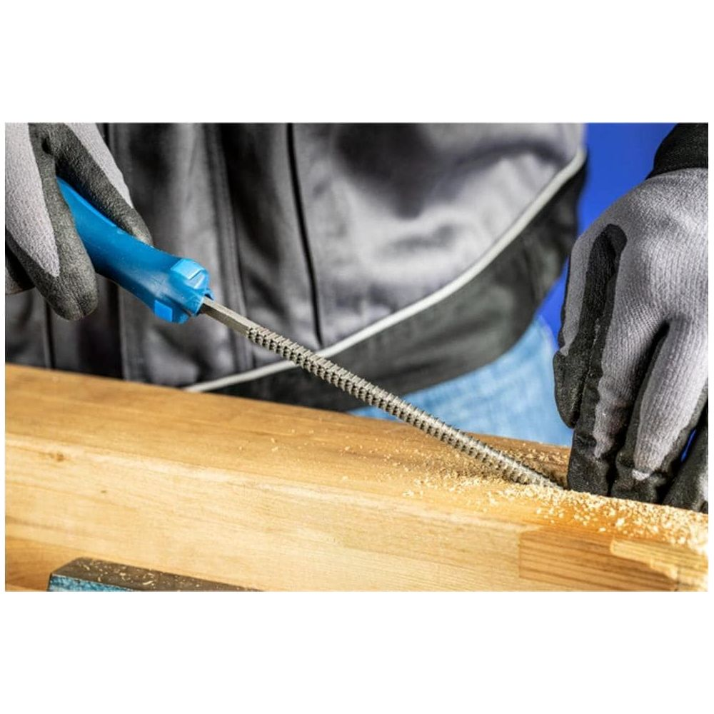 Person bearbeitet Holz mit einer Raspel, Sägespäne liegen herum.