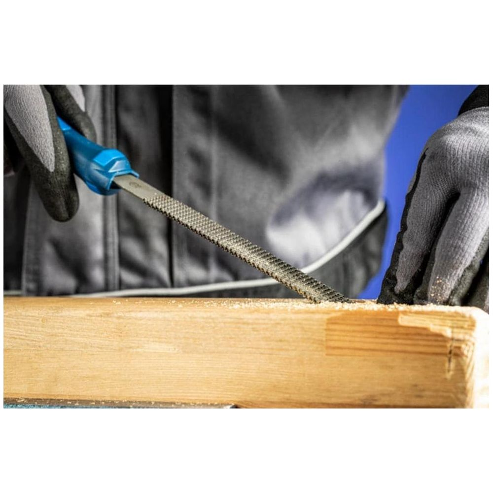Hände mit Handschuhen benutzen eine Raspel, um Holz zu bearbeiten.