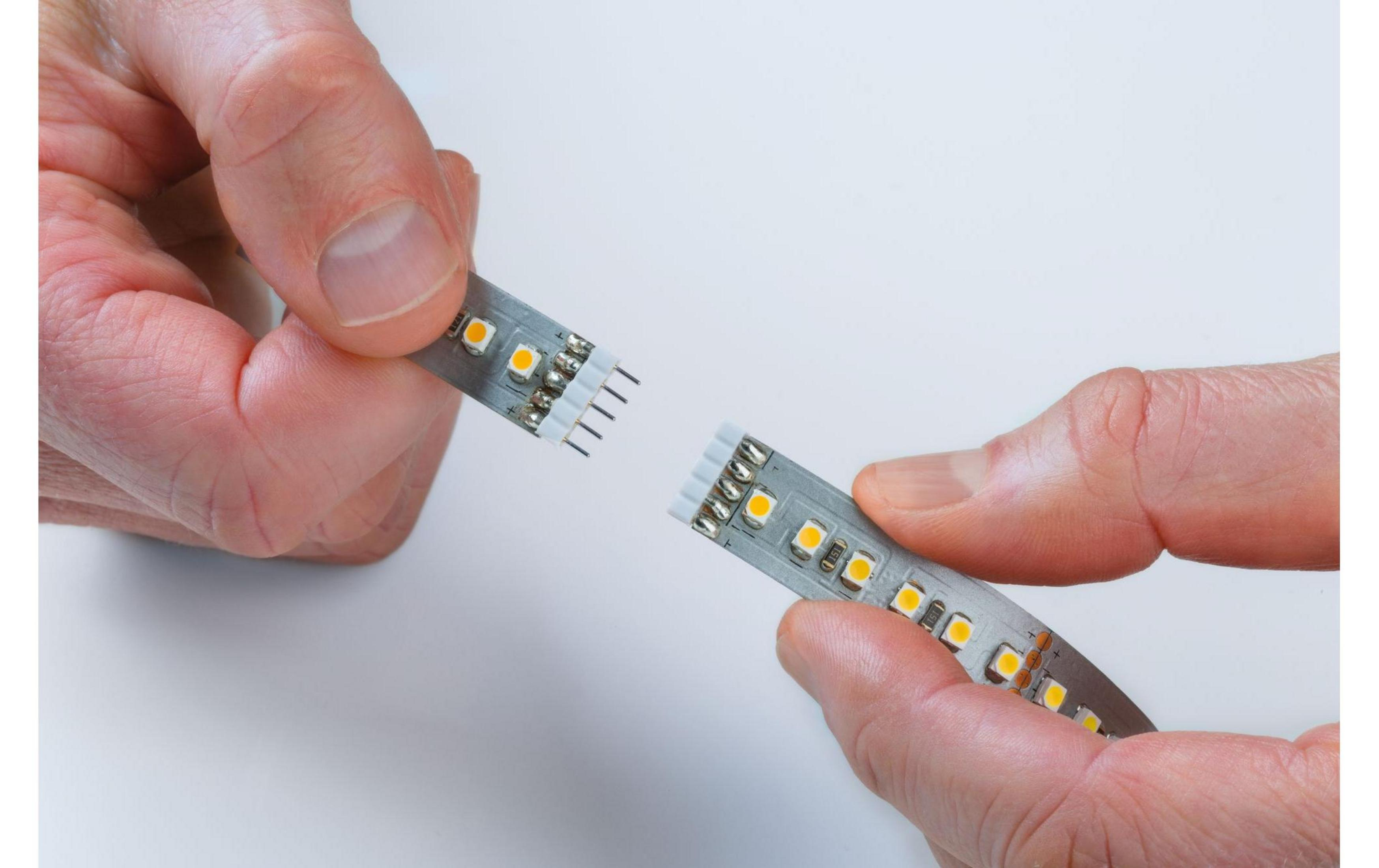 Hände verbinden LED-Streifen mit kleinen gelben Lichtern und silbernen Anschlüssen.