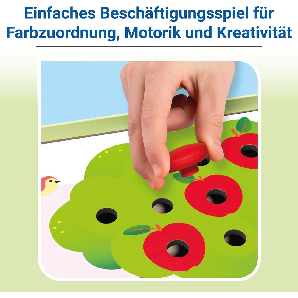 Mano inserisce pomello mela rossa su gioco albero verde. Uccellino a sinistra.